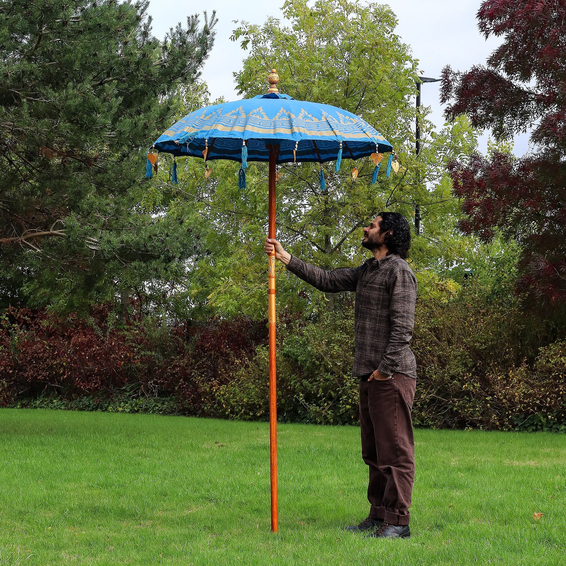 Handcrafted Decorative Parasol - Medium - Turquoise with blue canopy and hanging tassels, held upright on a long orange pole by Quintessential Holistic Health Ltd