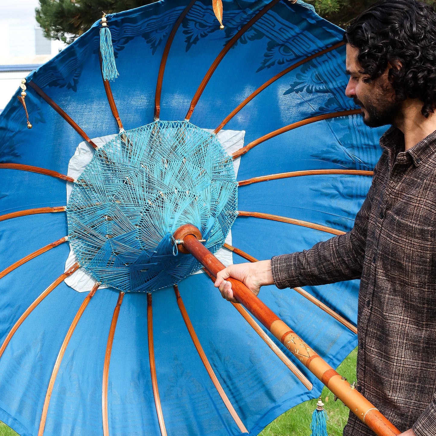 Handcrafted Decorative Parasol - Medium - Turquoise showing blue canopy lining, brown ribs and circular woven centre, held open by Quintessential Holistic Health Ltd