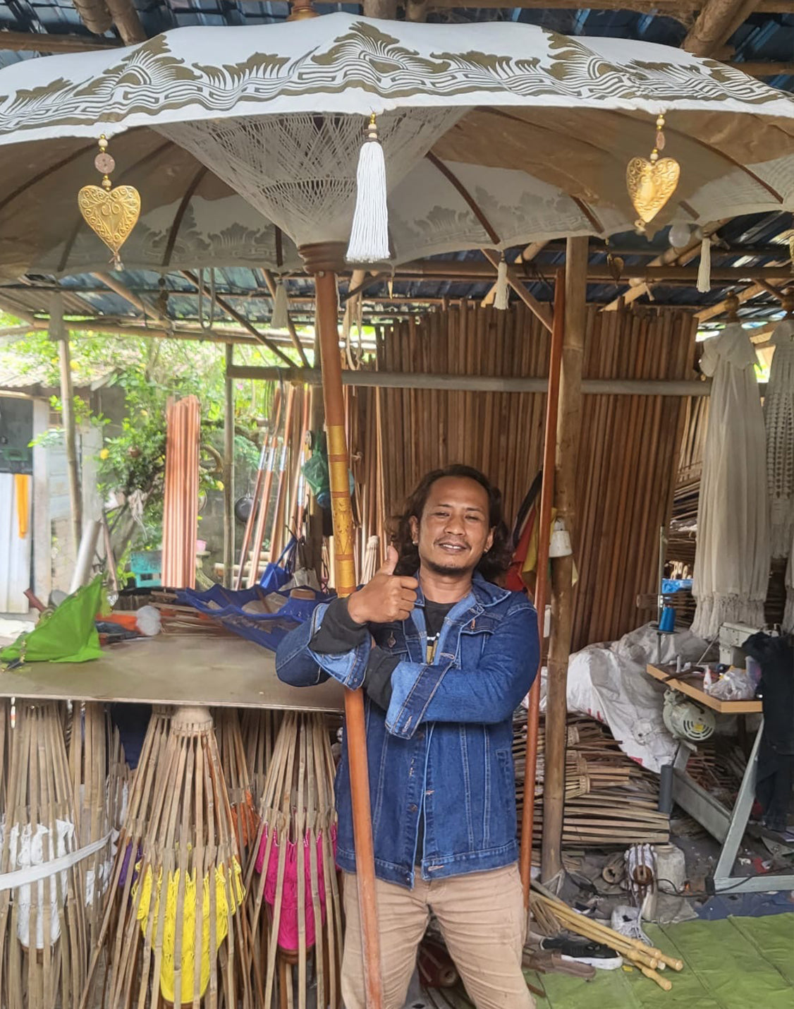 Handcrafted Decorative Parasol - Large - Turquoise with a pale patterned canopy, white tassel and gold heart ornaments above a man by Quintessential Holistic Health Ltd