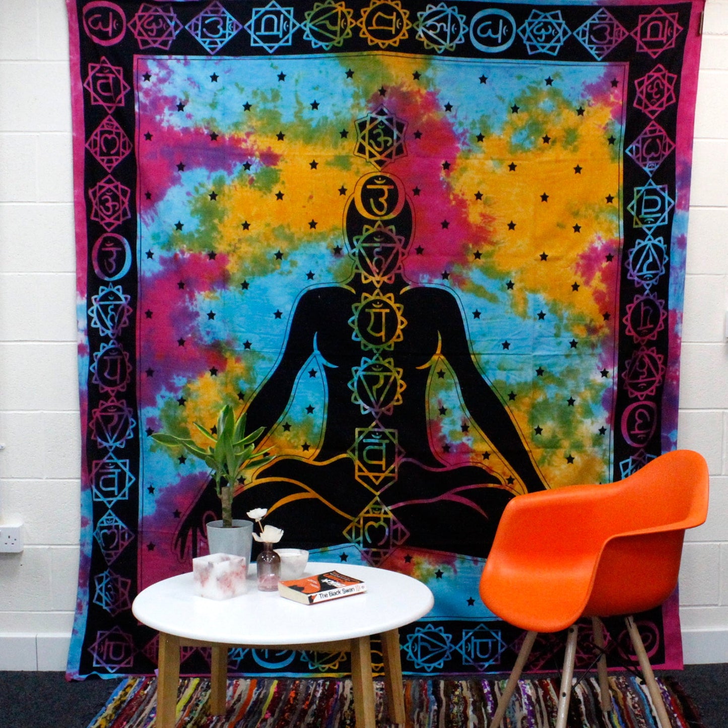 Cotton Wall Hanging or Bedspread - Double - Chakra Buddha displayed behind an orange chair and round white table by Quintessential Holistic Health Ltd
