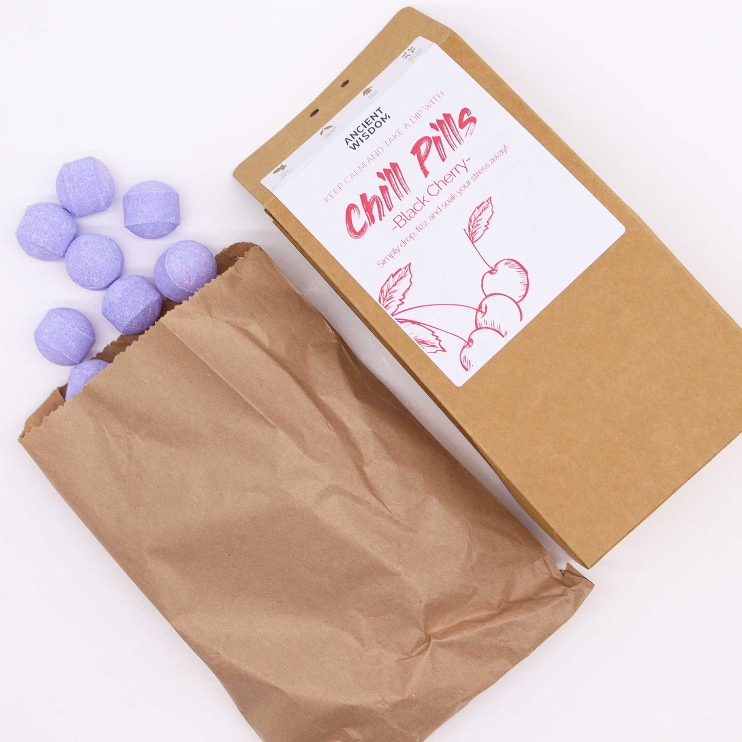 Vegan Bath Bomb Chill Pills Gift Pack - Black Cherry - 350g, open kraft box beside a paper bag and scattered purple tablets, by Quintessential Holistic Health Ltd