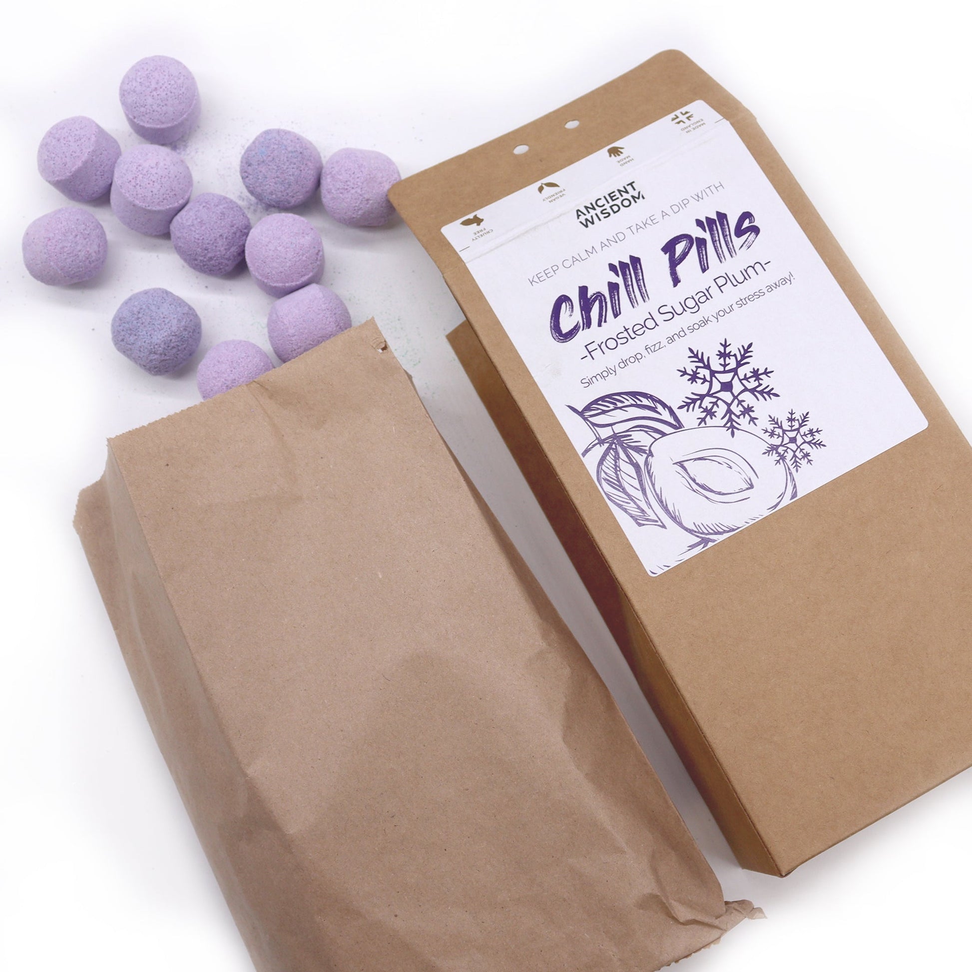 Vegan Bath Bomb Chill Pills - Frosted Sugar Plum - 350g, open kraft box beside a paper bag and scattered lilac tablets, by Quintessential Holistic Health Ltd