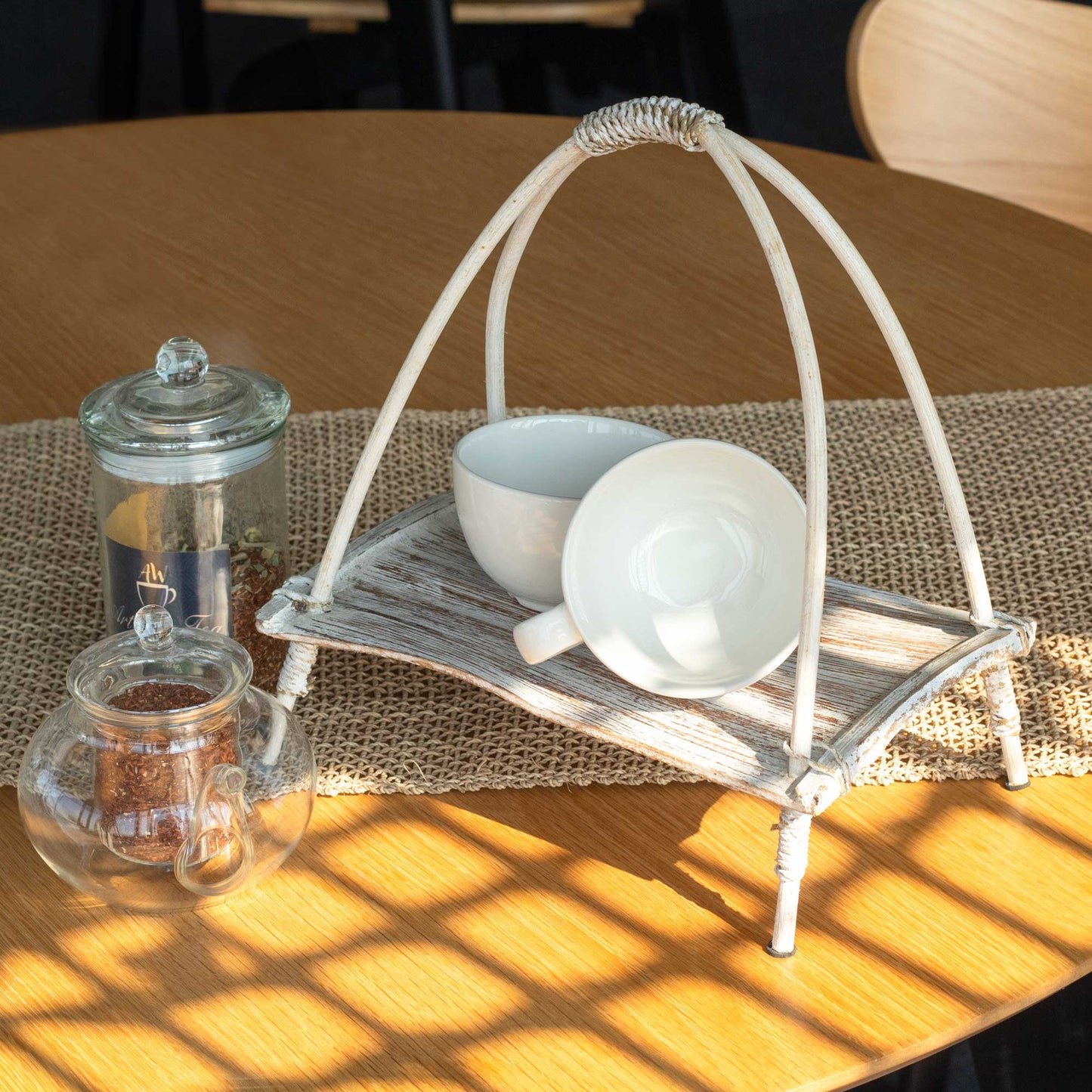 Coconut Leaf Tea Stand - Whitewash, holding white crockery and folded napkins beside glass jars by Quintessential Holistic Health Ltd