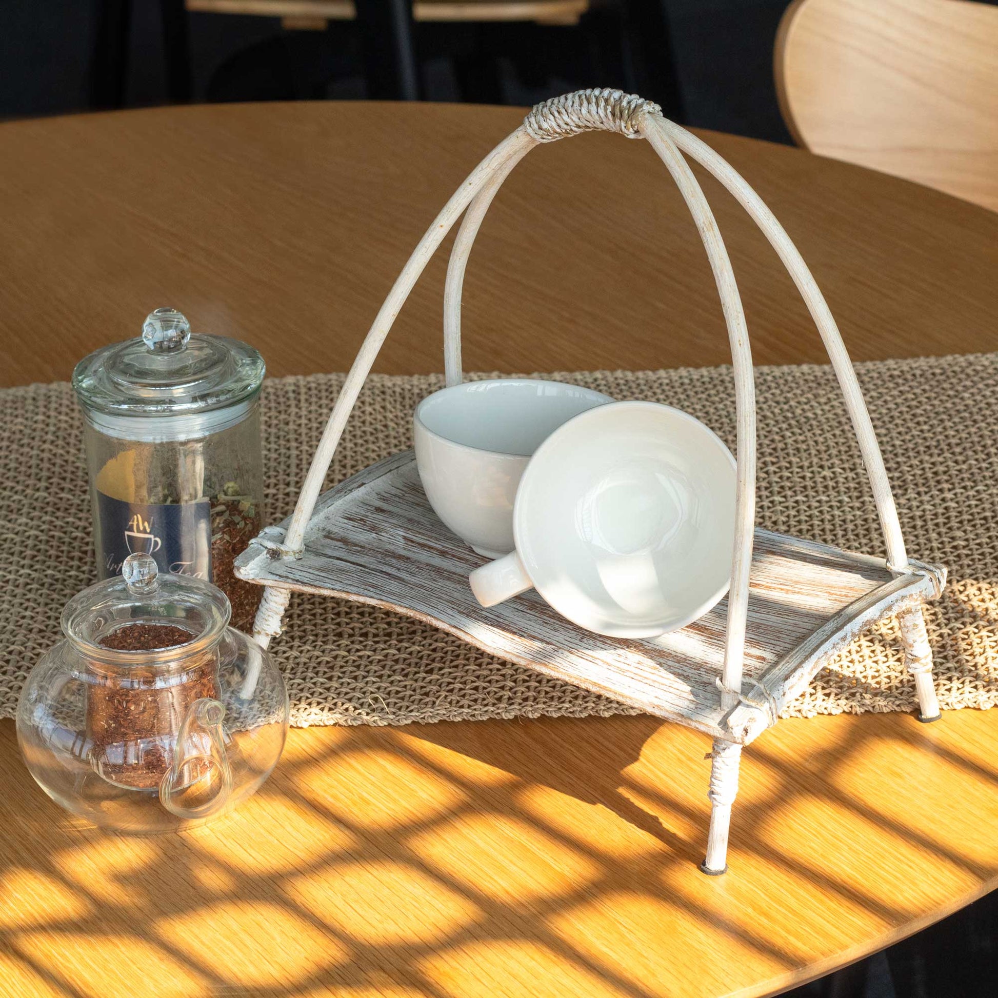 Coconut Leaf Tea Stand - Whitewash, holding white crockery and folded napkins beside glass jars by Quintessential Holistic Health Ltd