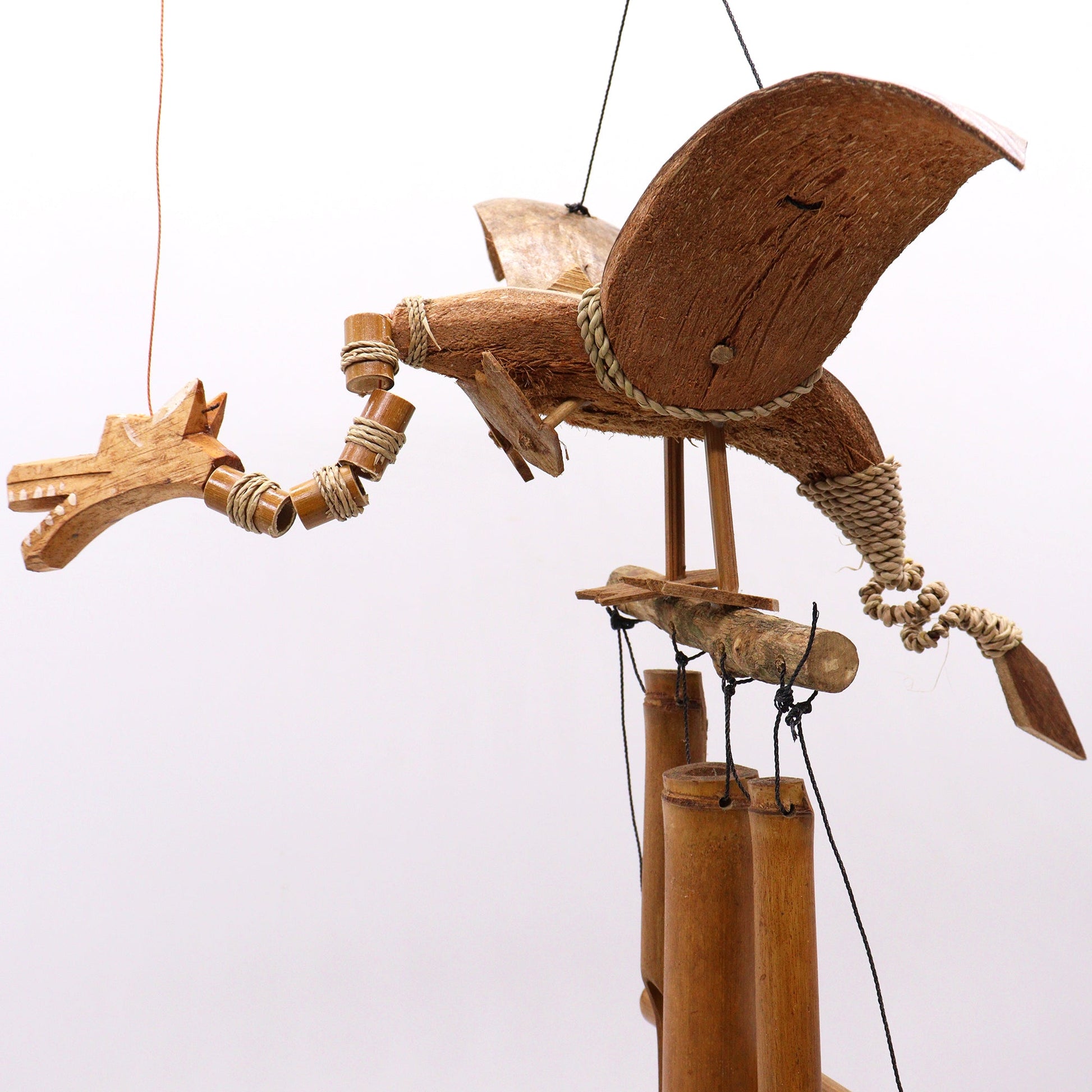 Handcrafted Coconut Shell Wind Chime - Dragon, side view of the winged dragon above three suspended chimes by Quintessential Holistic Health Ltd