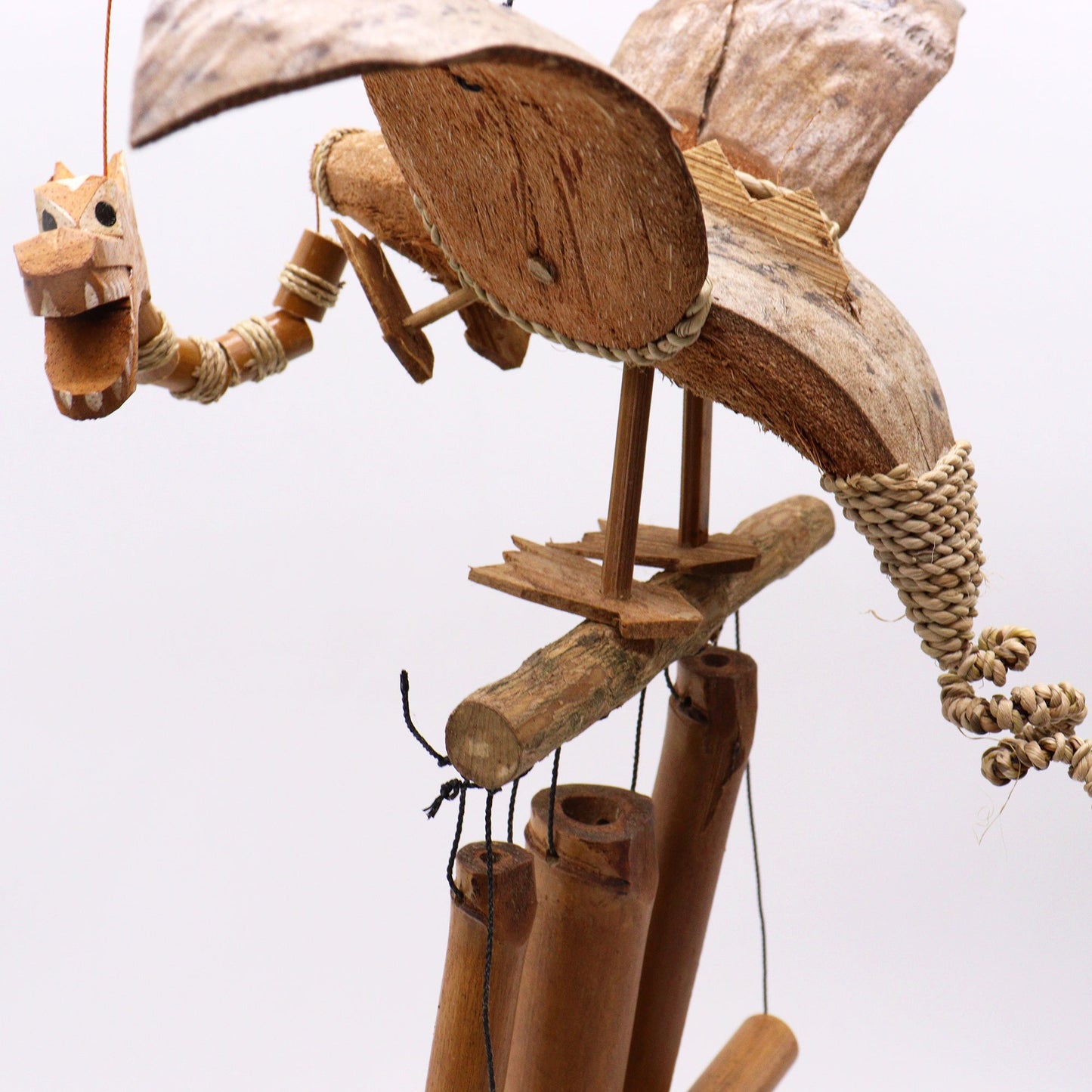 Handcrafted Coconut Shell Wind Chime - Dragon, detailed winged dragon with segmented tail above tubular chimes by Quintessential Holistic Health Ltd