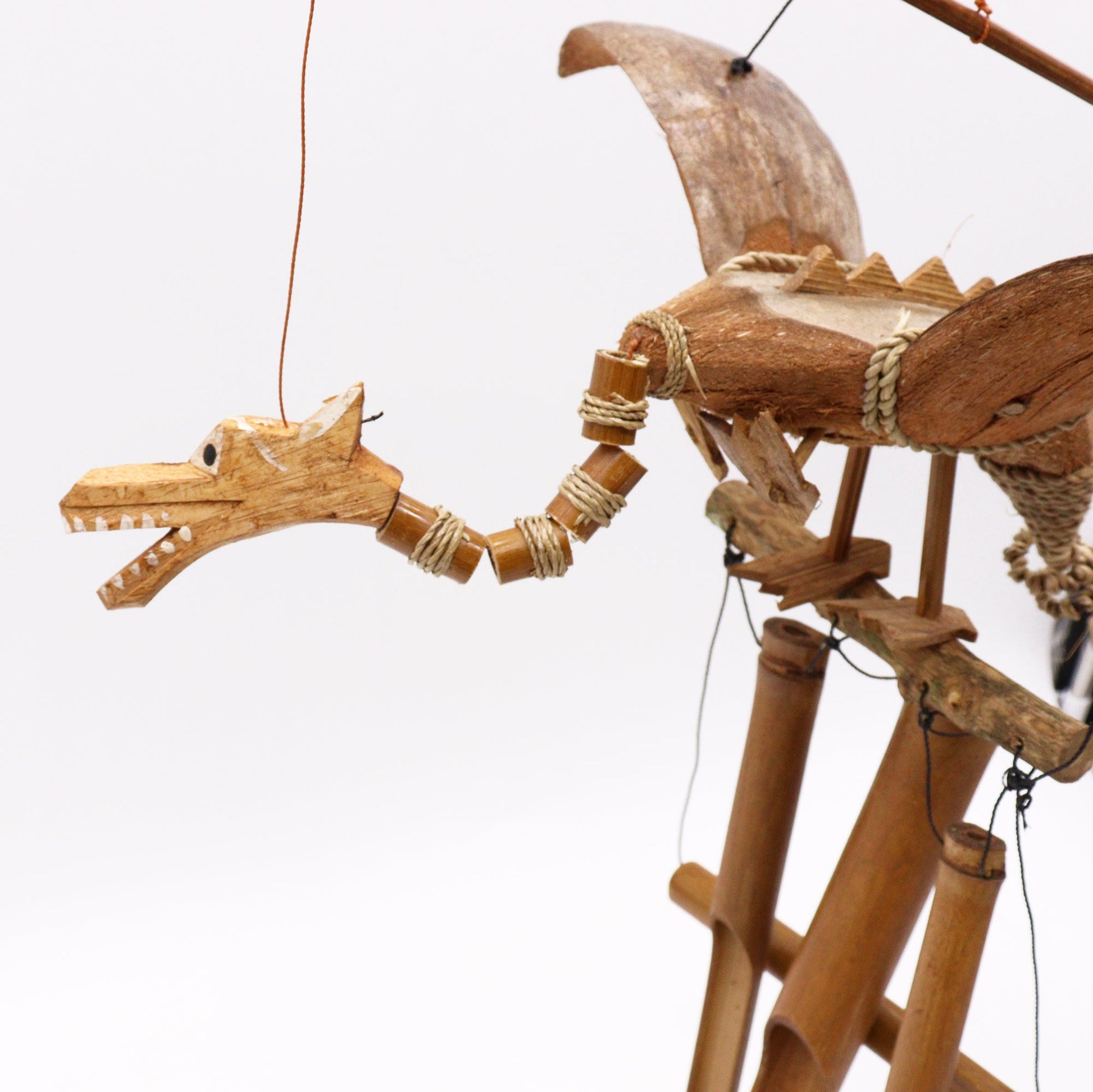 Handcrafted Coconut Shell Wind Chime - Dragon, close view of the head, segmented neck and raised wings by Quintessential Holistic Health Ltd