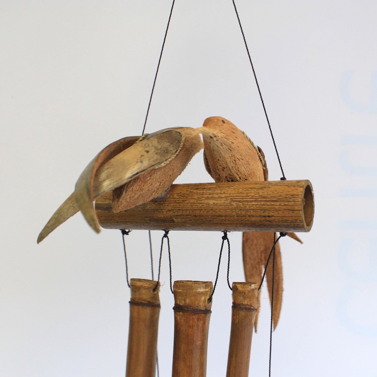 Handcrafted Coconut Shell and Bamboo Wind Chime - Love Birds close-up with two carved birds perched above hanging tubes by Quintessential Holistic Health Ltd