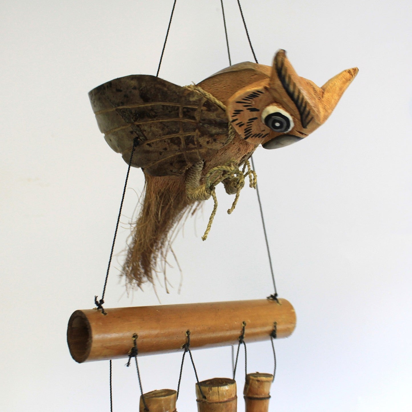 Handcrafted Coconut Shell and Bamboo Wind Chime - Owl close-up with a large blue eye, raised wings and a feather-like tail by Quintessential Holistic Health Ltd
