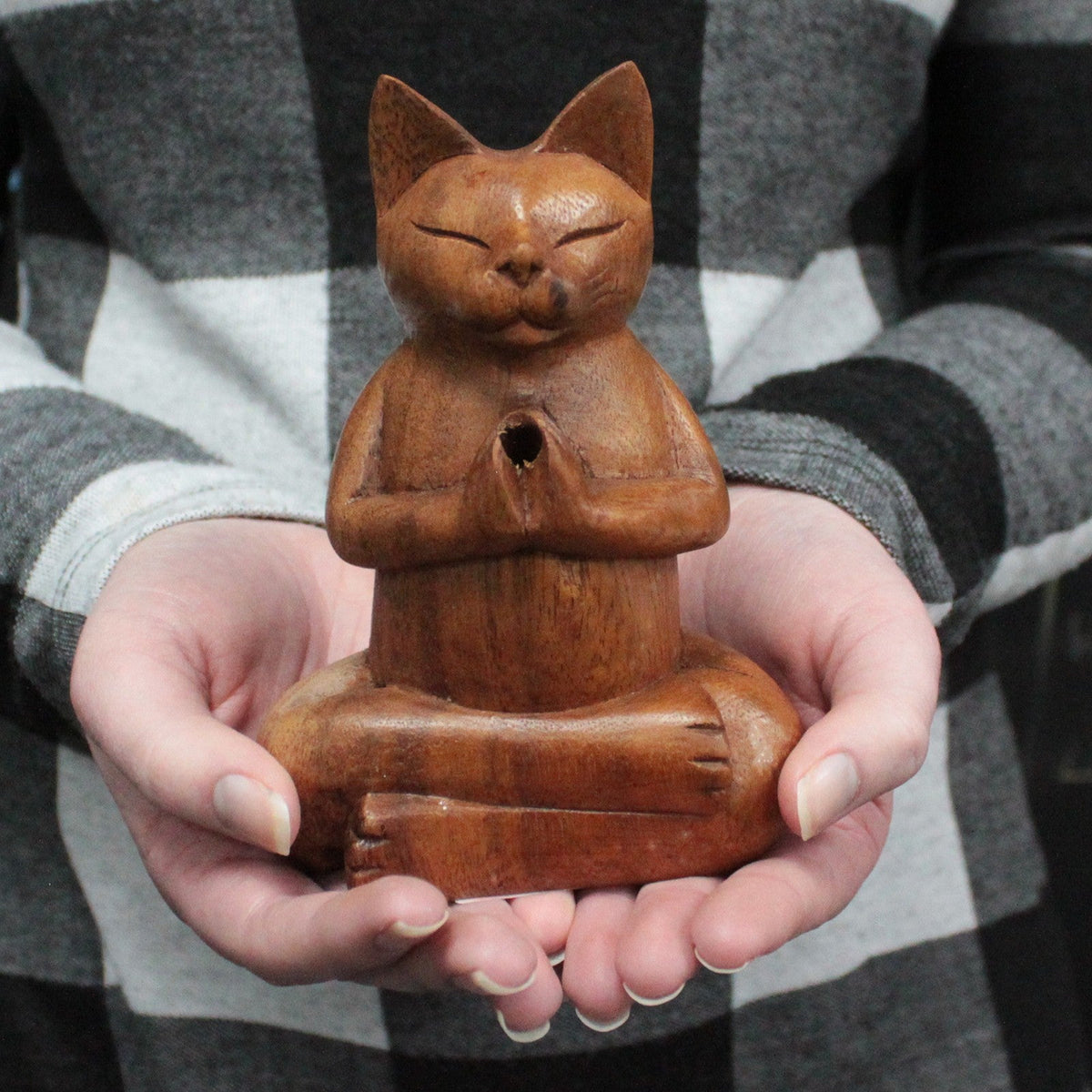 Hand-Carved Suar Wood Incense Cone Burner - Medium Yoga Cat, a seated brown cat figure with joined paws displayed in two hands by Quintessential Holistic Health Ltd