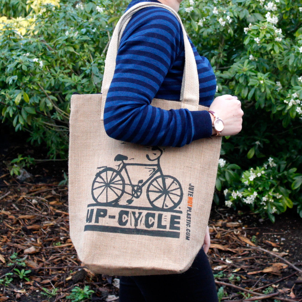 Eco-Friendly Jute Bag - Up Cycle - Random Black or Yellow, carried over one shoulder with a dark bicycle graphic by Quintessential Holistic Health Ltd