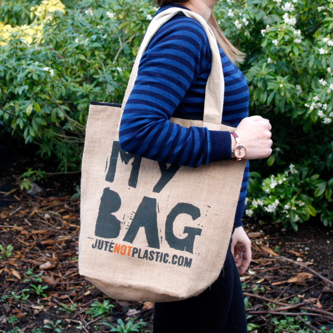 Eco-Friendly Jute Bag - My Bag - Random Black or Yellow shown carried over the shoulder outdoors with black lettering by Quintessential Holistic Health Ltd
