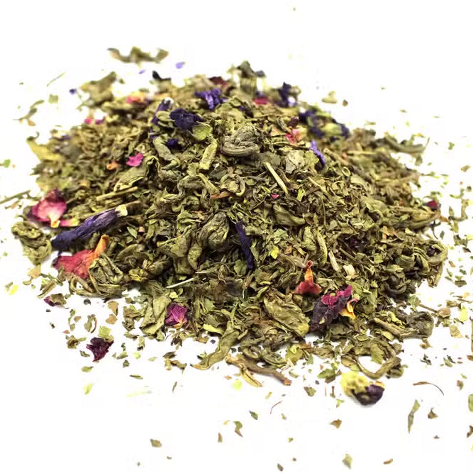 Serenity Souk green tea blend, loose mound with pink petals and curled green leaves from Quintessential Holistic Health.