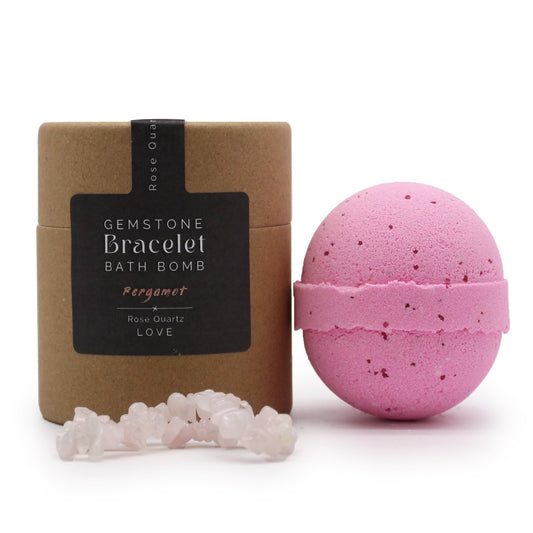 Rose Quartz bracelet bath bomb, pink bath bomb beside a labelled kraft box and pale stone chips from Quintessential Holistic Health.