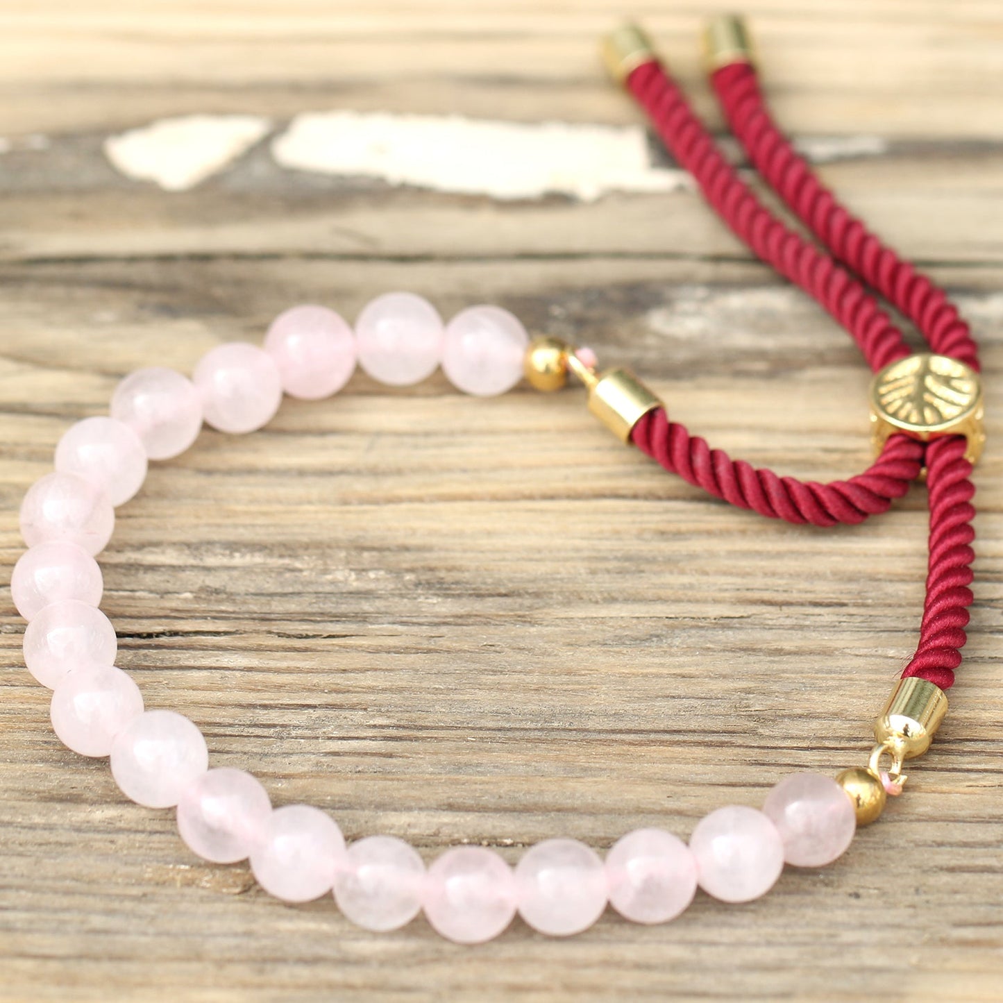 Unisex Handcrafted 18K Gold Plated Gemstone Bracelet - Burgundy String / Rose Quartz product packaging on clean background from Quintessential Holistic Health Ltd