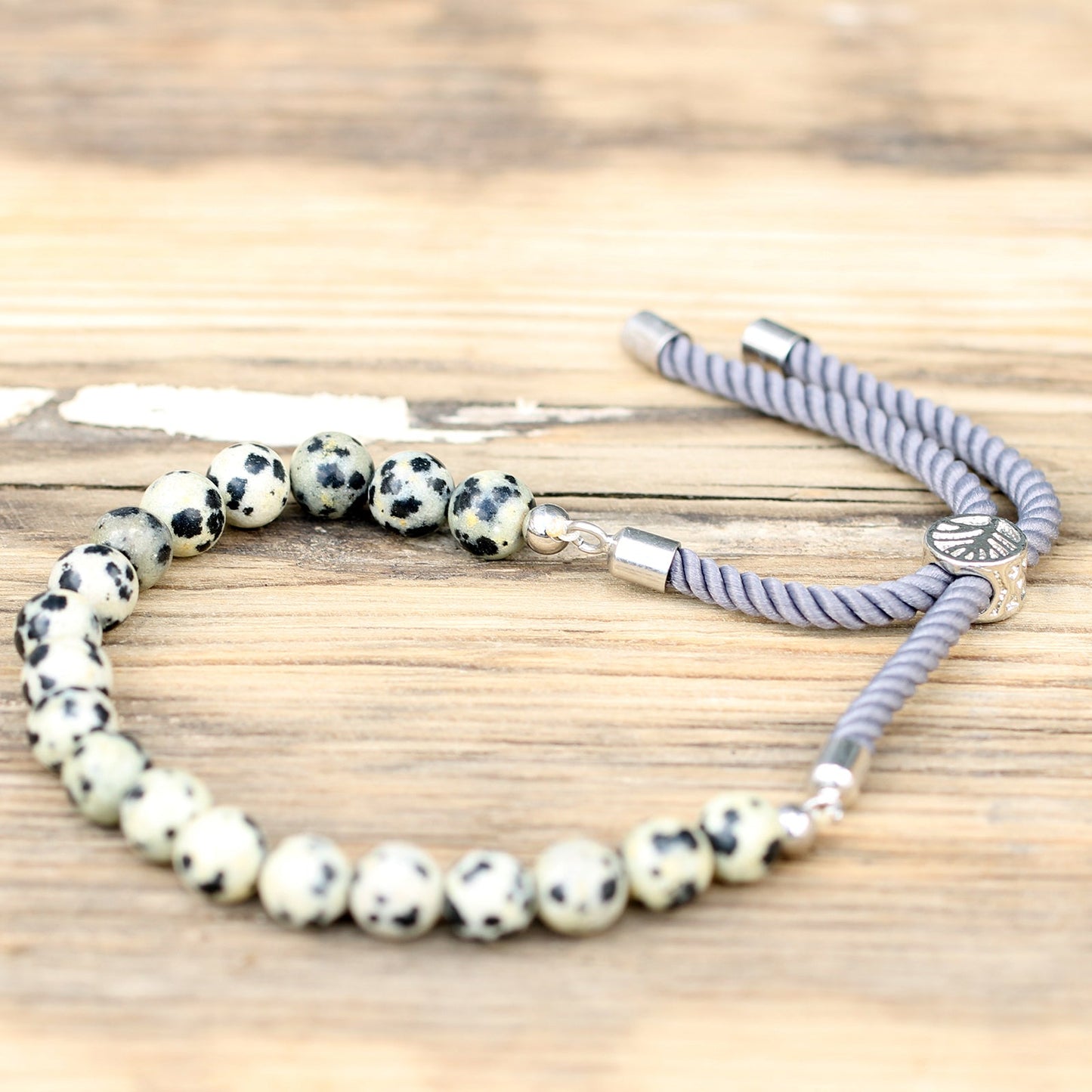 Unisex Handcrafted 925 Silver Plated Gemstone Bracelet - Charcoal String / Dalmatian Jasper product packaging on clean background from Quintessential Holistic Health Ltd