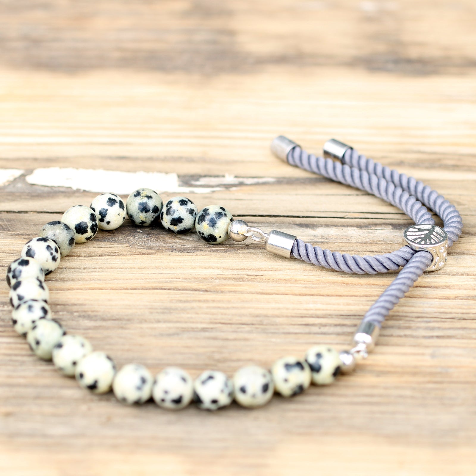 Unisex Handcrafted 925 Silver Plated Gemstone Bracelet - Charcoal String / Dalmatian Jasper product packaging on clean background from Quintessential Holistic Health Ltd