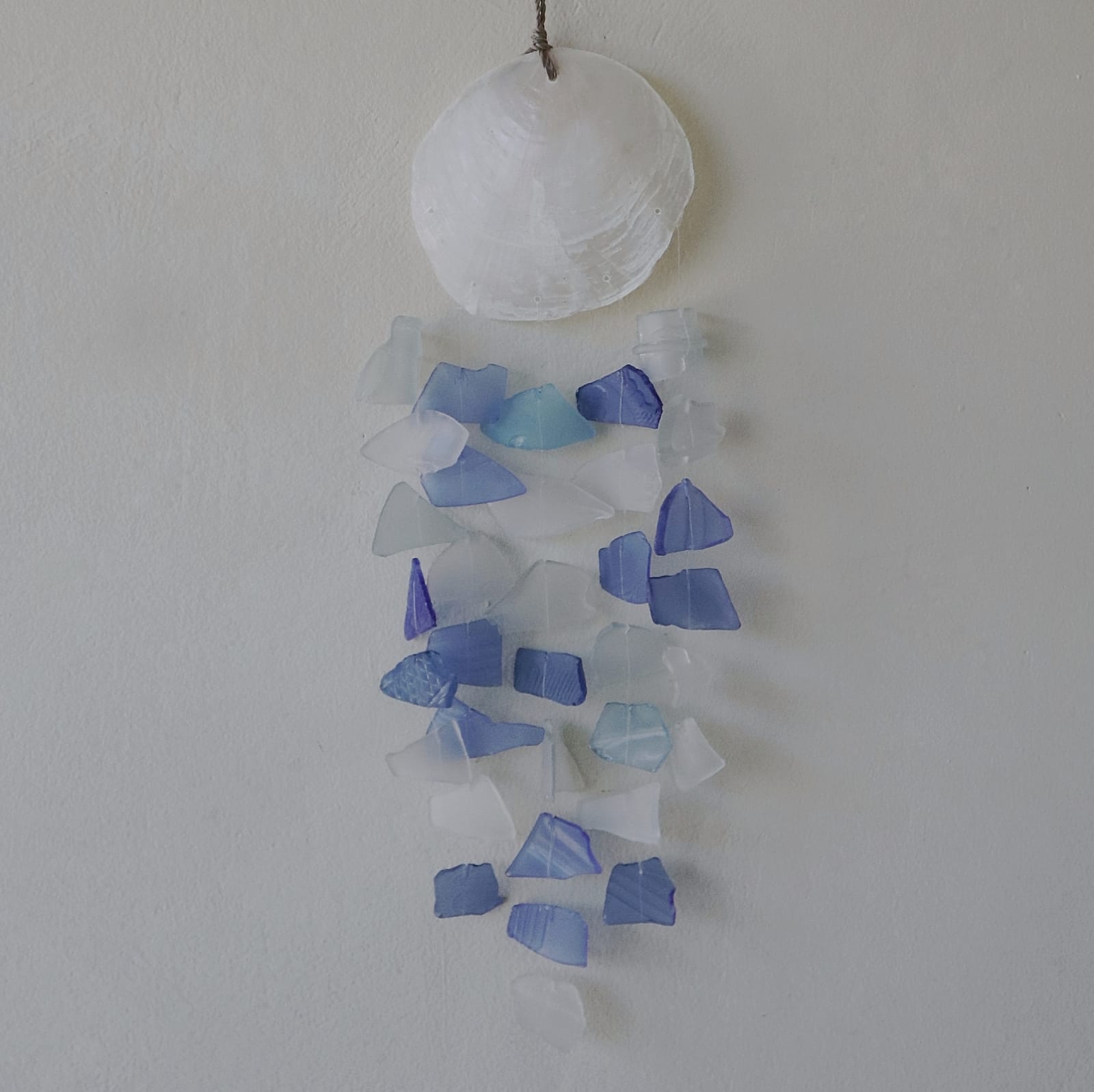 Recycled Glass Wind Chime - Blue & White Glass Drop hanging against a grey wall with blue and white pieces by Quintessential Holistic Health Ltd
