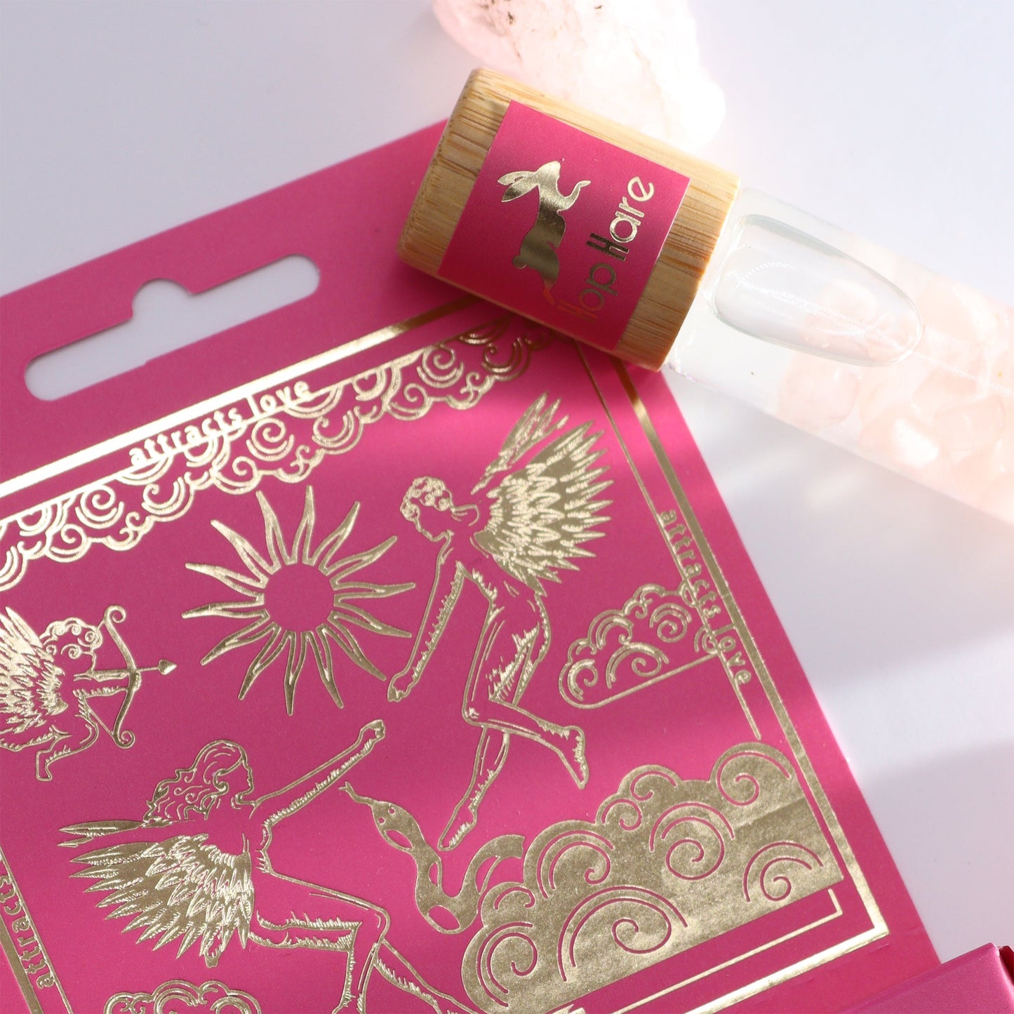 Gemstone Tarot Essential Oil Roll-On - Rose Quartz - The Lovers with bottle resting across the pink and gold illustrated box by Quintessential Holistic Health Ltd