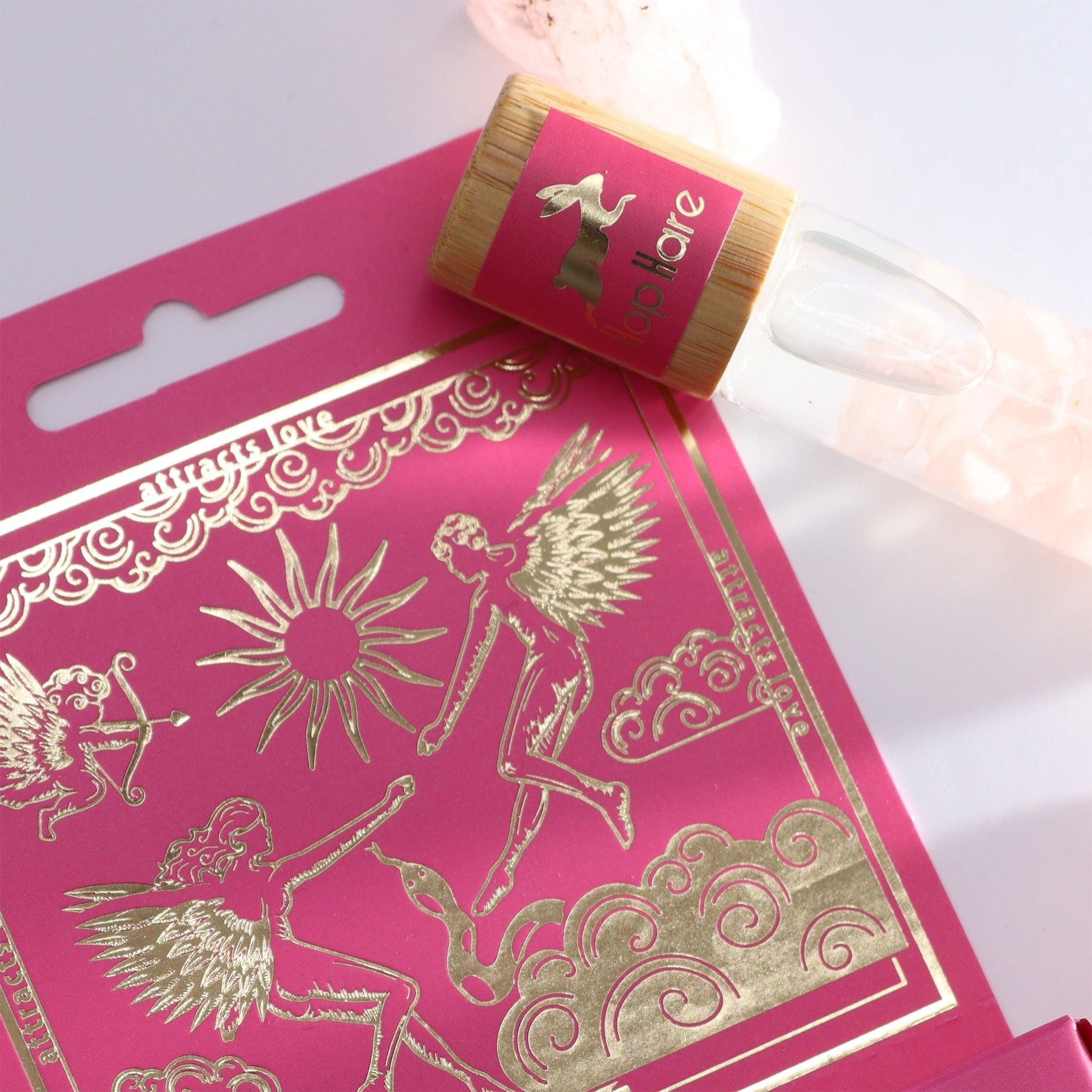 Gemstone Tarot Essential Oil Roll-On - Rose Quartz - The Lovers with bottle resting across the pink and gold illustrated box by Quintessential Holistic Health Ltd