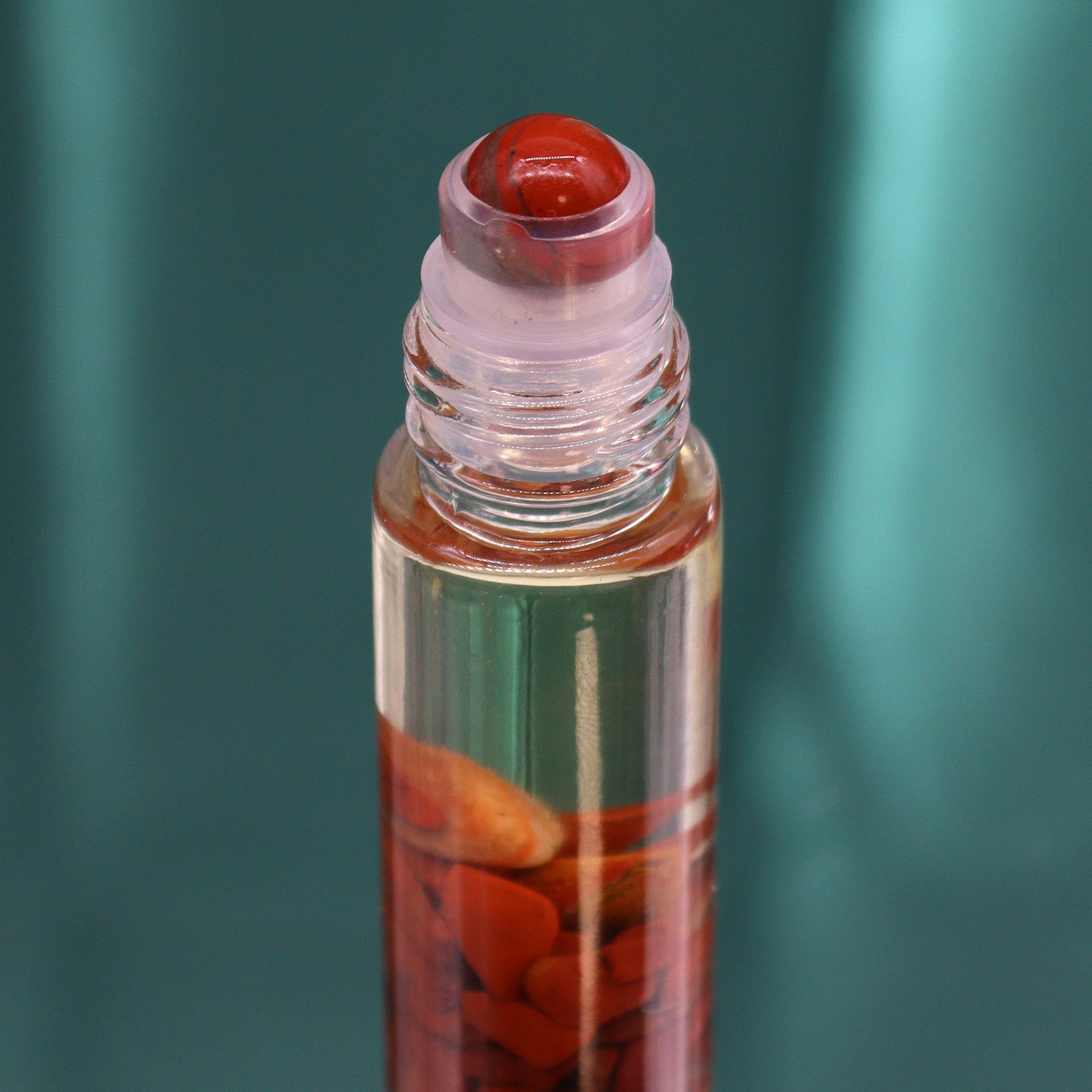 Gemstone Tarot Essential Oil Roll-On - Red Jasper - The Devil showing a red roller top above orange chips by Quintessential Holistic Health Ltd