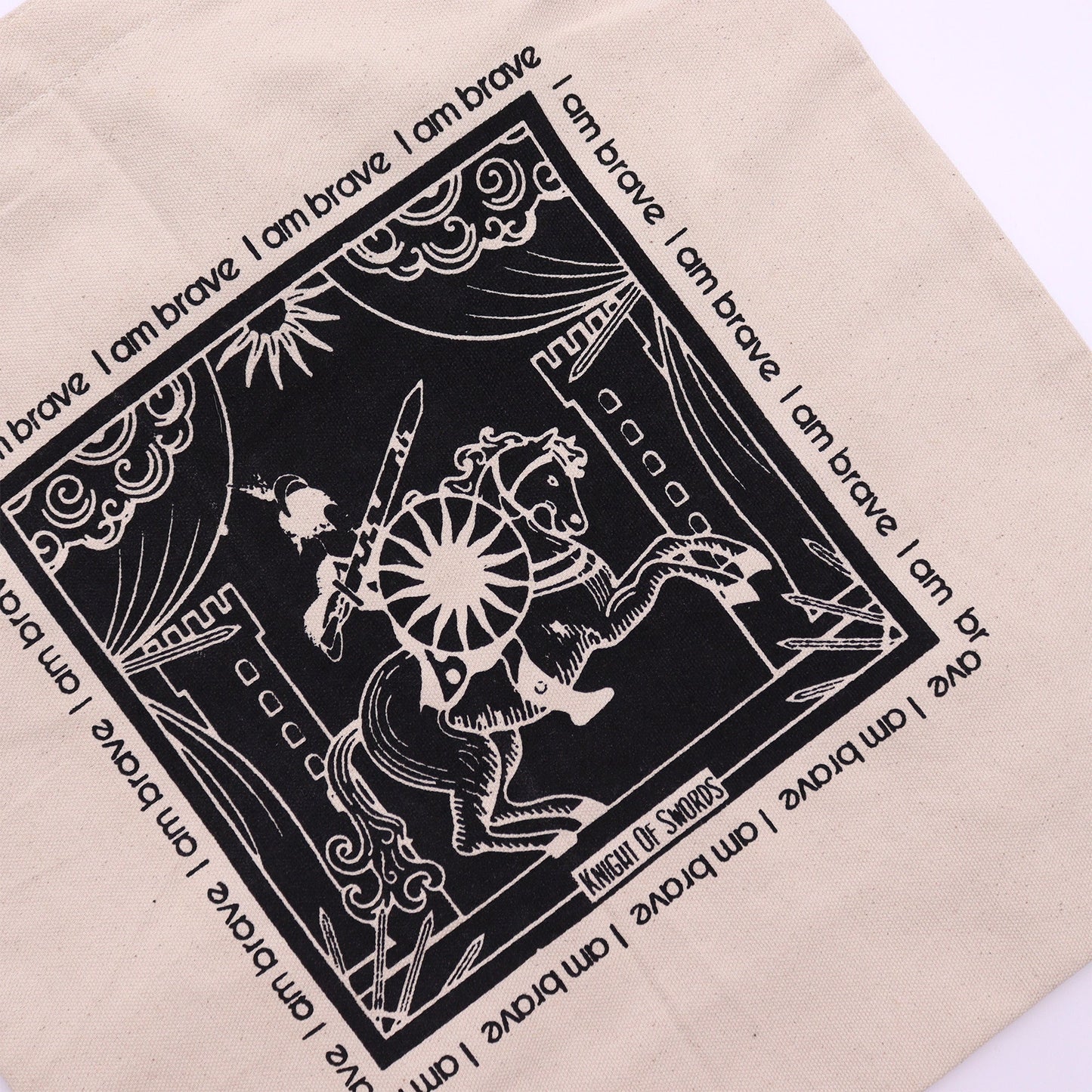 Knight of Swords Tarot Cotton Canvas Tote Bag - I Am Brave with a close-up black illustration of a knight, sword and sun by Quintessential Holistic Health Ltd