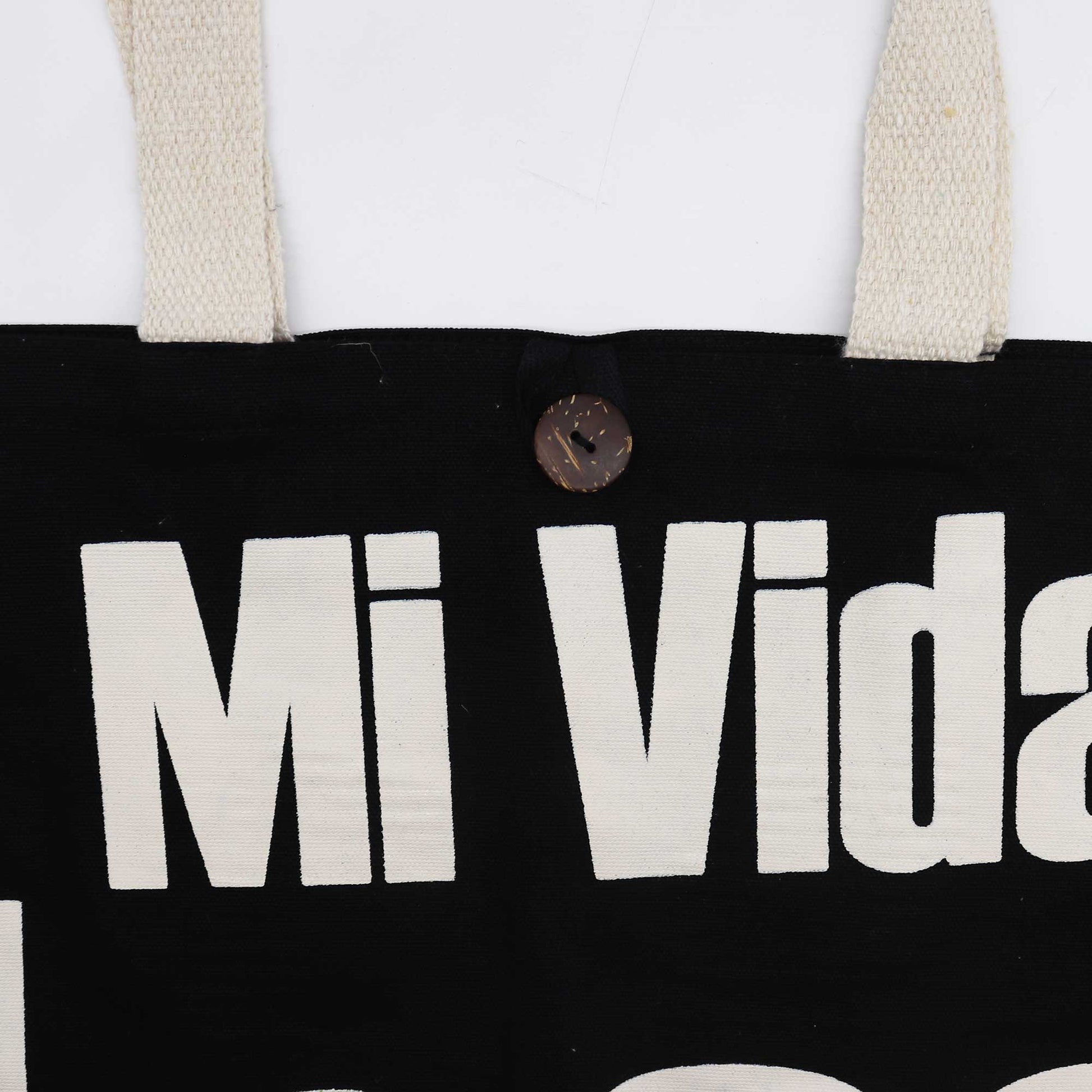 Iconic Cotton Classic Tote Bag - Mi Vida Loca - Black & Natural, close-up of cream Mi Vida lettering, natural straps and brown button by Quintessential Holistic Health Ltd