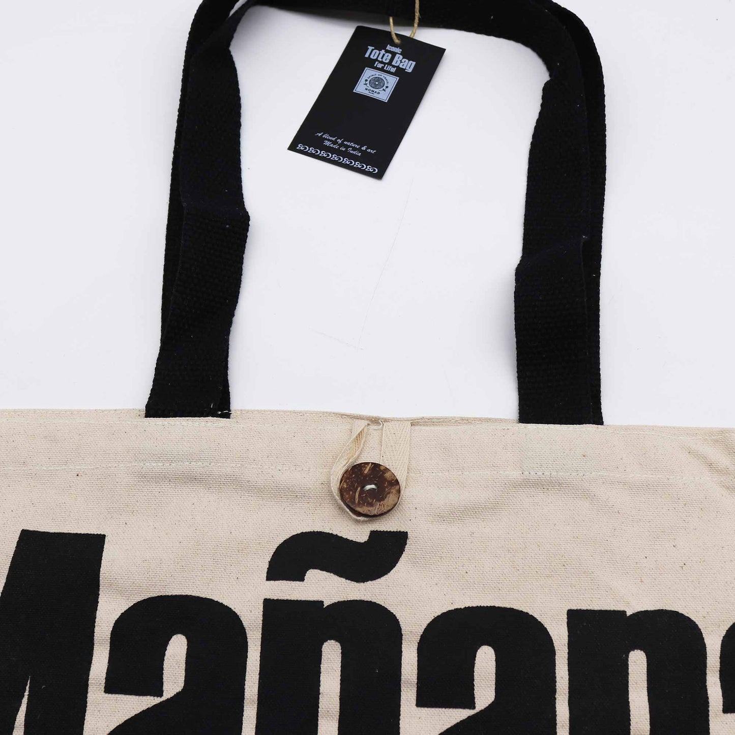 Iconic Cotton Classic Tote Bag - Mañana Mañana - Natural, close-up of black Mañana lettering, brown button, black trim and hanging tag by Quintessential Holistic Health Ltd