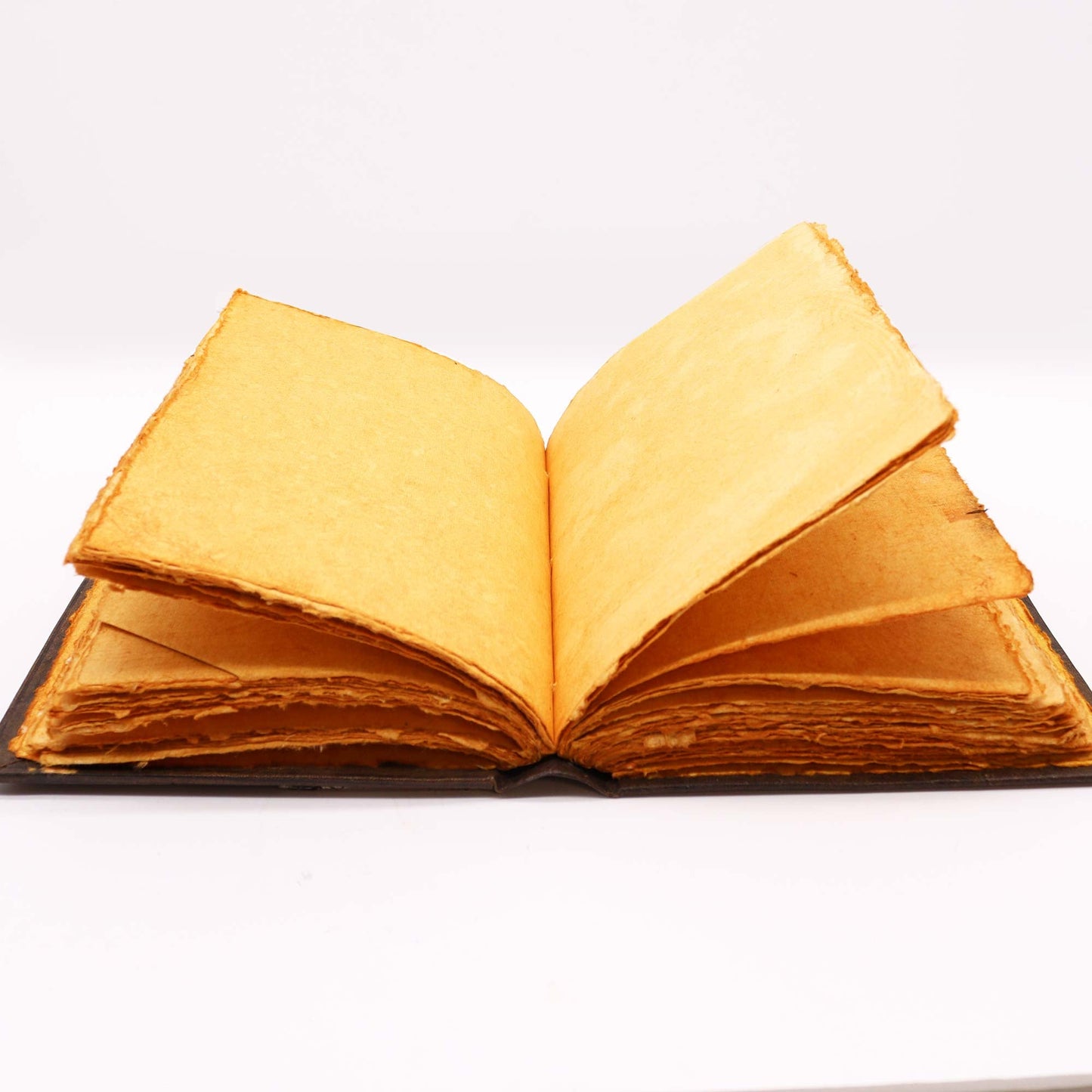 Extra-Large Brown Leather Deckle-Edged Journal - Zinc Triple Moon, open with several golden-toned pages raised and layered by Quintessential Holistic Health Ltd