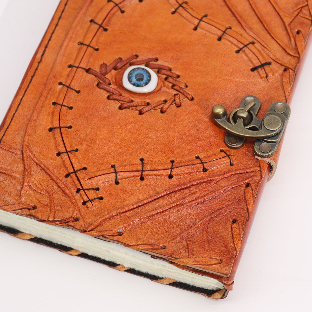Large Light Brown Leather Notebook – Evil Eye, Deckle Edge, close-up showing the eye motif, black stitching and metal clasp, by Quintessential Holistic Health Ltd