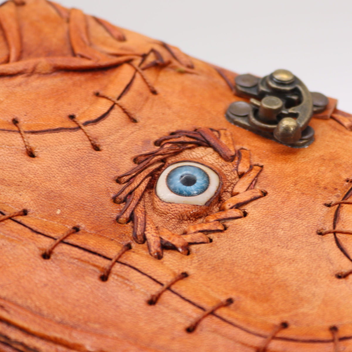 Medium Light Brown Leather Notebook – Evil Eye, Deckle Edge, close-up of the eye motif, stitched brown cover and metal clasp, by Quintessential Holistic Health Ltd