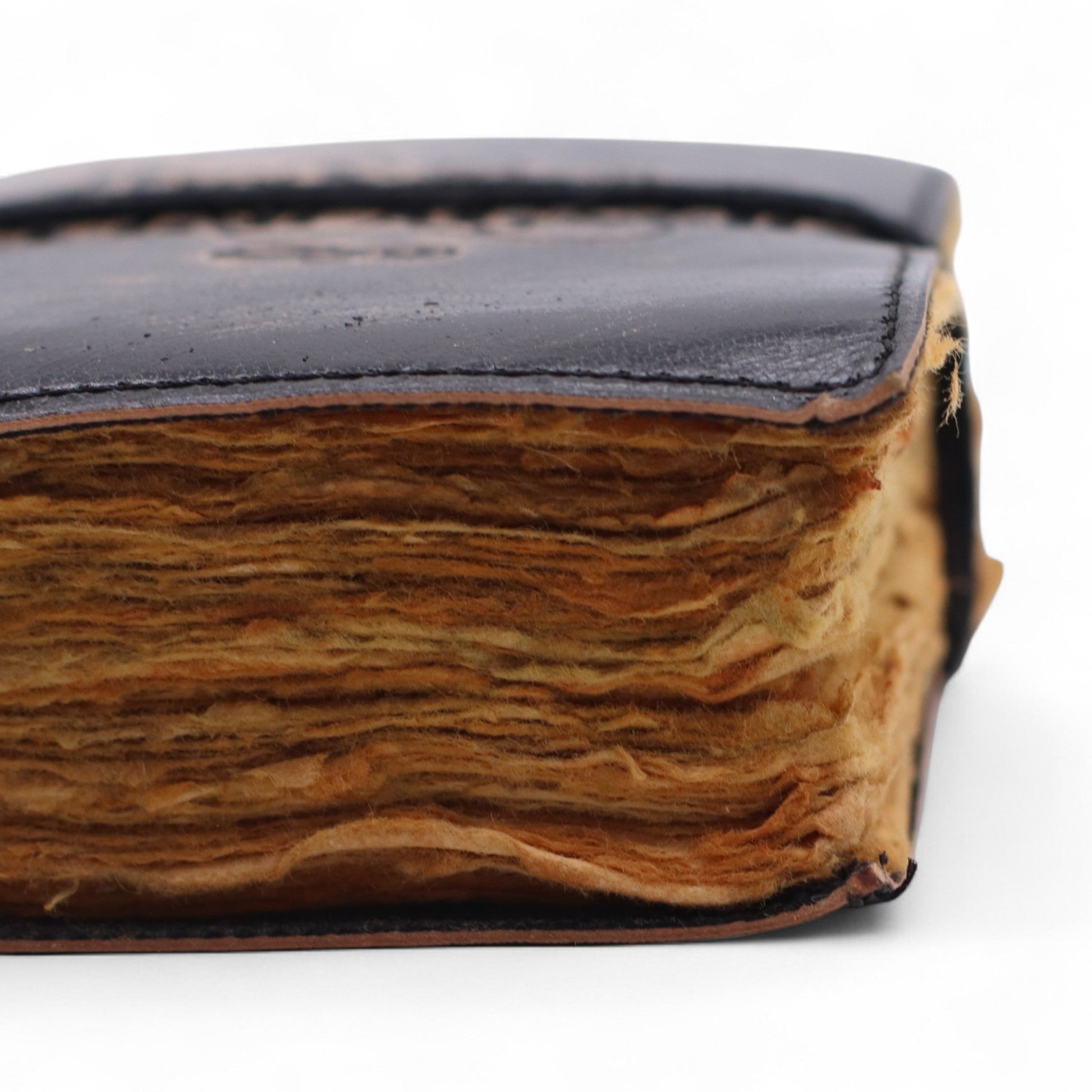 Small Black and Tan Leather Journal - The Stories I Tell Myself, close-up of thick, uneven tan page edges beneath a dark cover by Quintessential Holistic Health Ltd