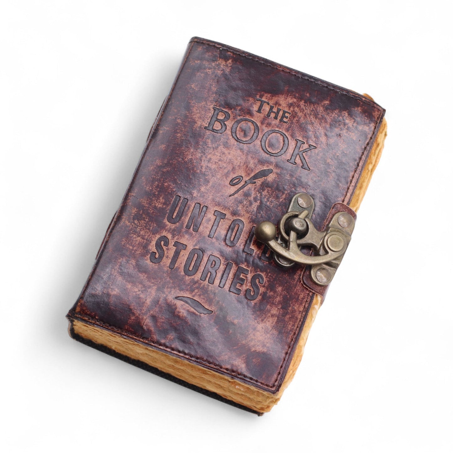 Small Brown Leather Journal - The Book of Untold Stories, lying diagonally with a mottled cover, embossed lettering and ornate clasp by Quintessential Holistic Health Ltd