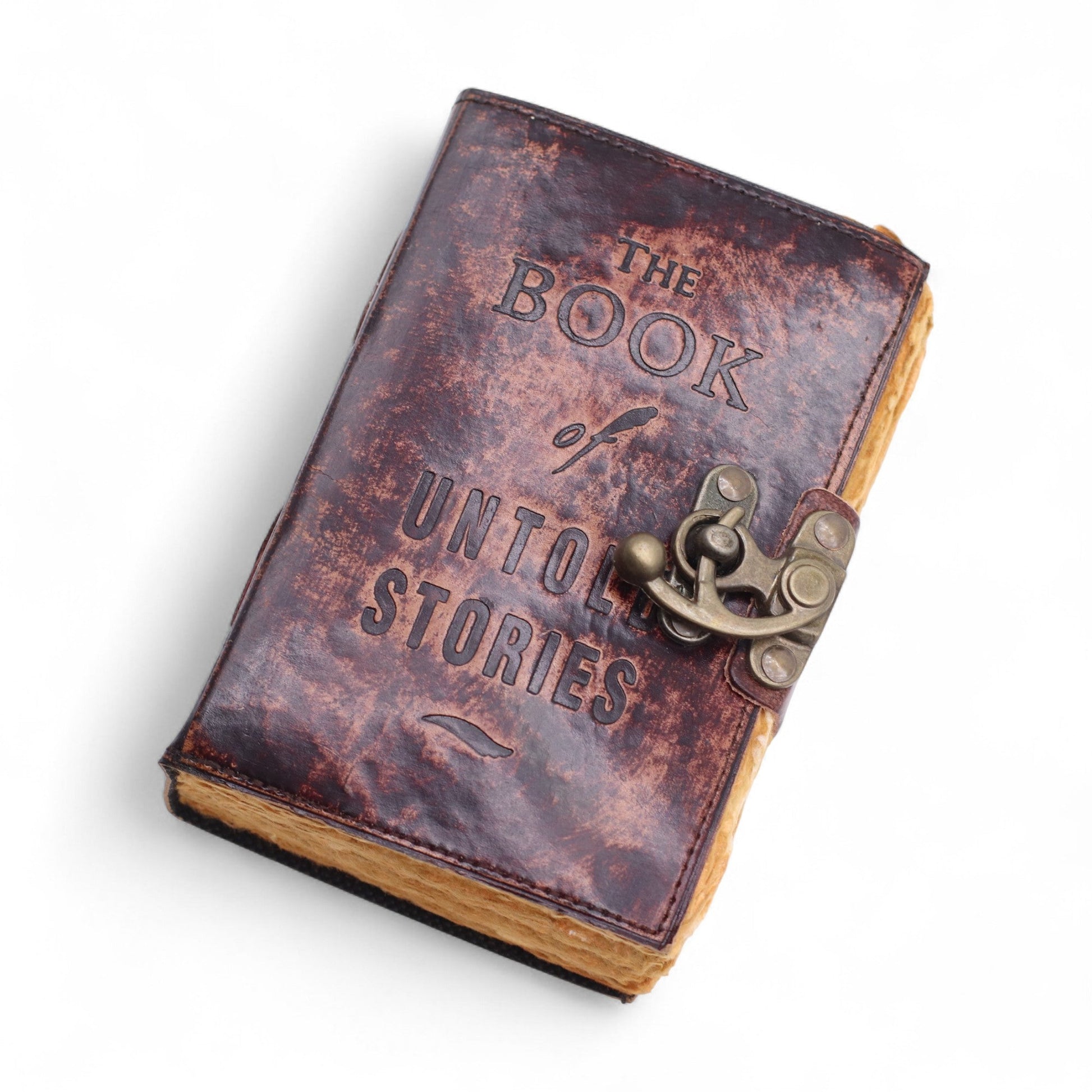 Small Brown Leather Journal - The Book of Untold Stories, lying diagonally with a mottled cover, embossed lettering and ornate clasp by Quintessential Holistic Health Ltd