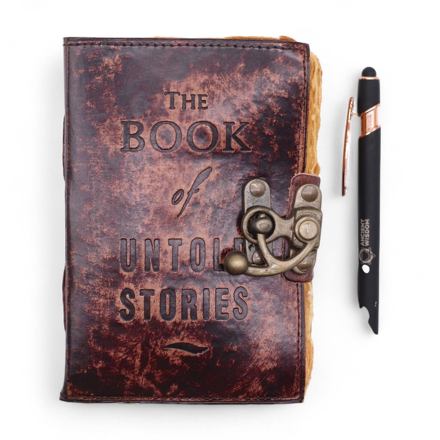 Small Brown Leather Journal - The Book of Untold Stories, shown closed beside a black pen with its ornate metal clasp fastened by Quintessential Holistic Health Ltd