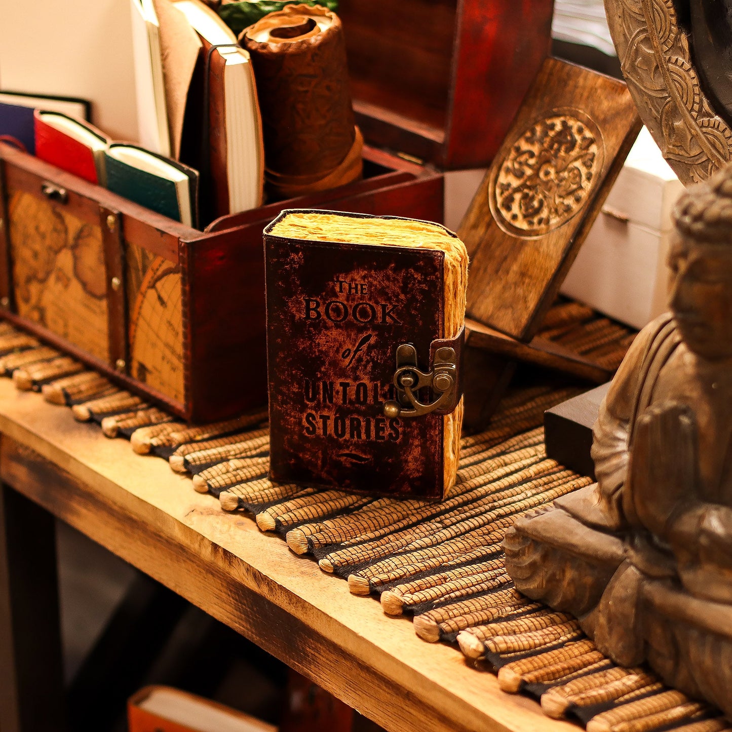 Small Brown Leather Journal - The Book of Untold Stories, standing closed among desk accessories with its embossed cover and clasp visible by Quintessential Holistic Health Ltd