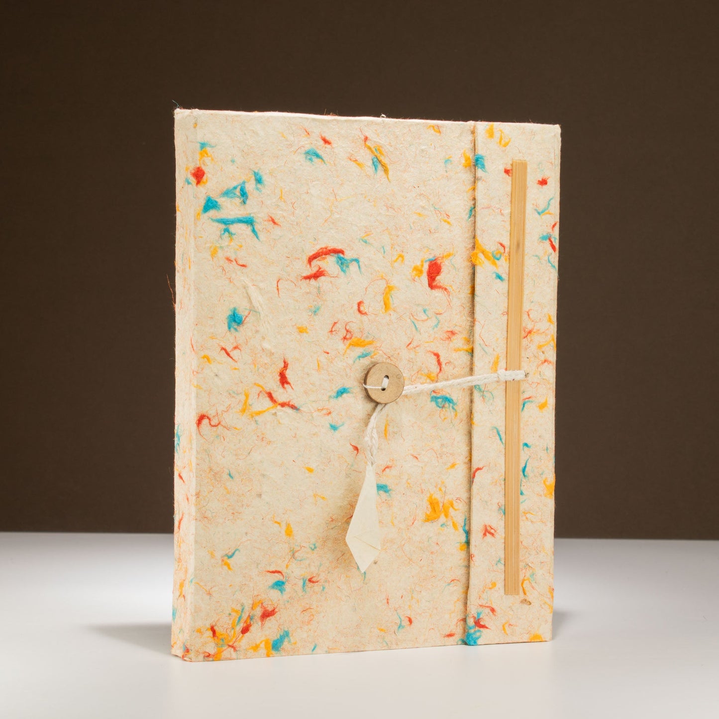 A5 Lokta Paper Notebook & Bookmark - Mixed Colour Cotton, showing the multicoloured flecked cover and cream cord upright, by Quintessential Holistic Health Ltd
