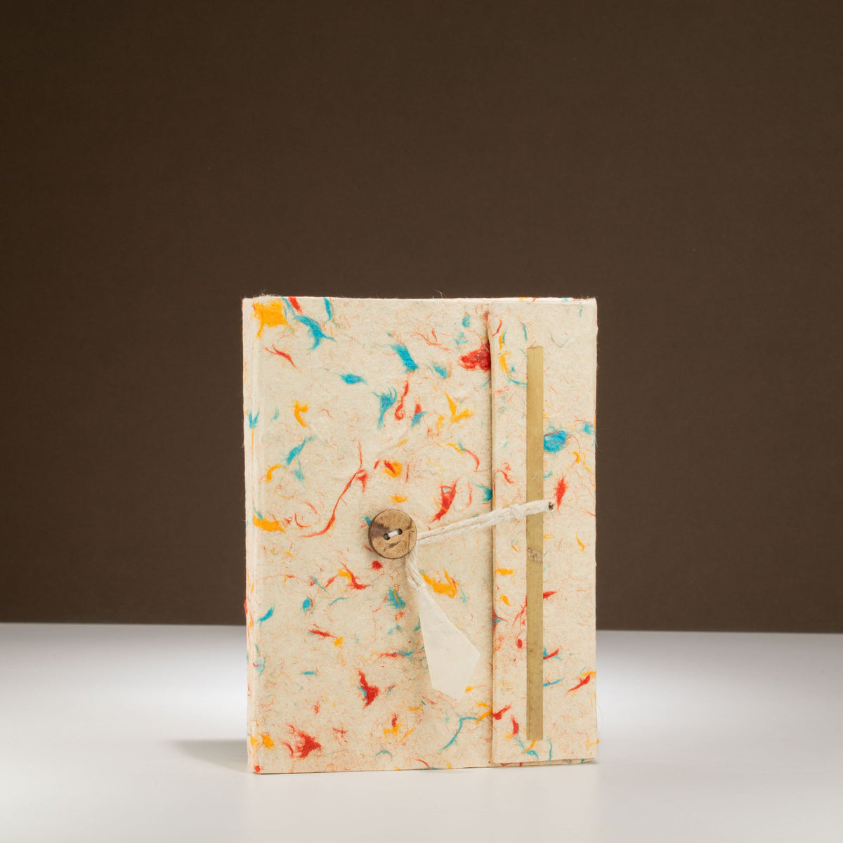 Eco-Friendly Lokta Paper Notebook - A6 - Mixed Colour Cotton with scattered colourful fibres, twin pale strips, cord and carved button by Quintessential Holistic Health Ltd
