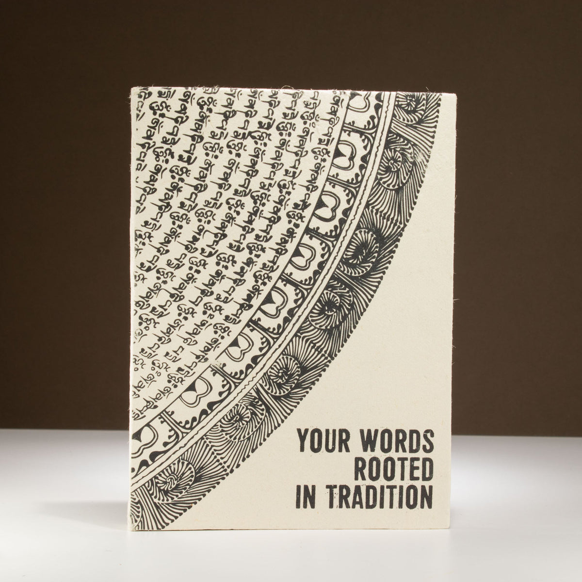 A5 Lokta Paper Journal & Bookmark - Your Words, Rooted in Tradition, showing the cream cover with black curved artwork upright, by Quintessential Holistic Health Ltd