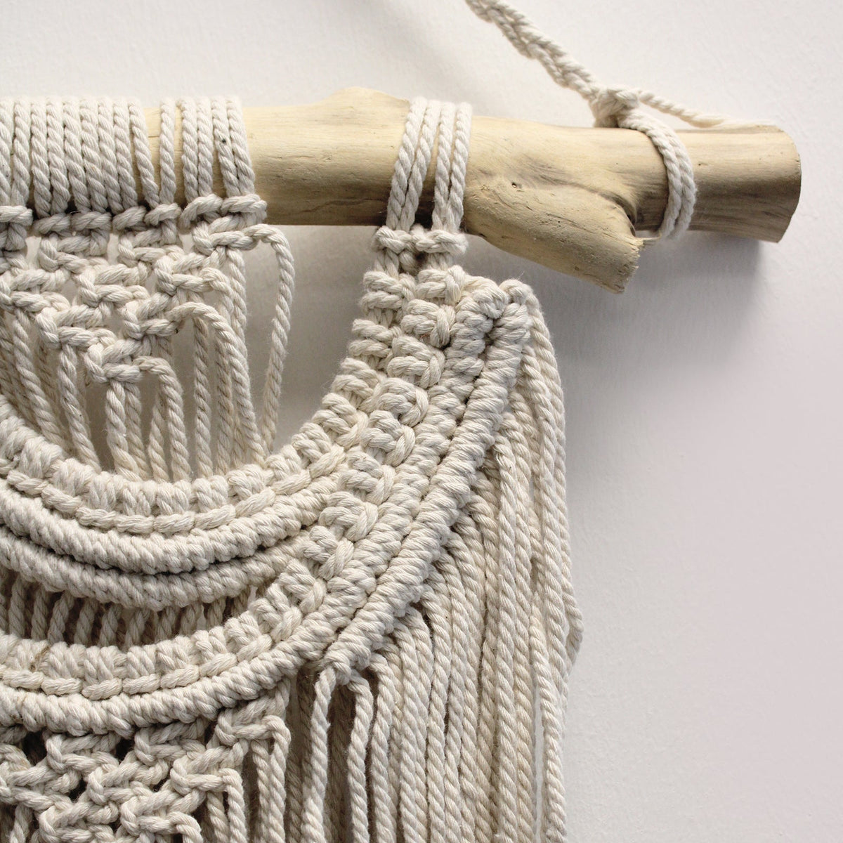Handcrafted Cotton Macramé Wall Hanging - Two Waves showing close-up layered curved knots looped over a wooden branch by Quintessential Holistic Health Ltd