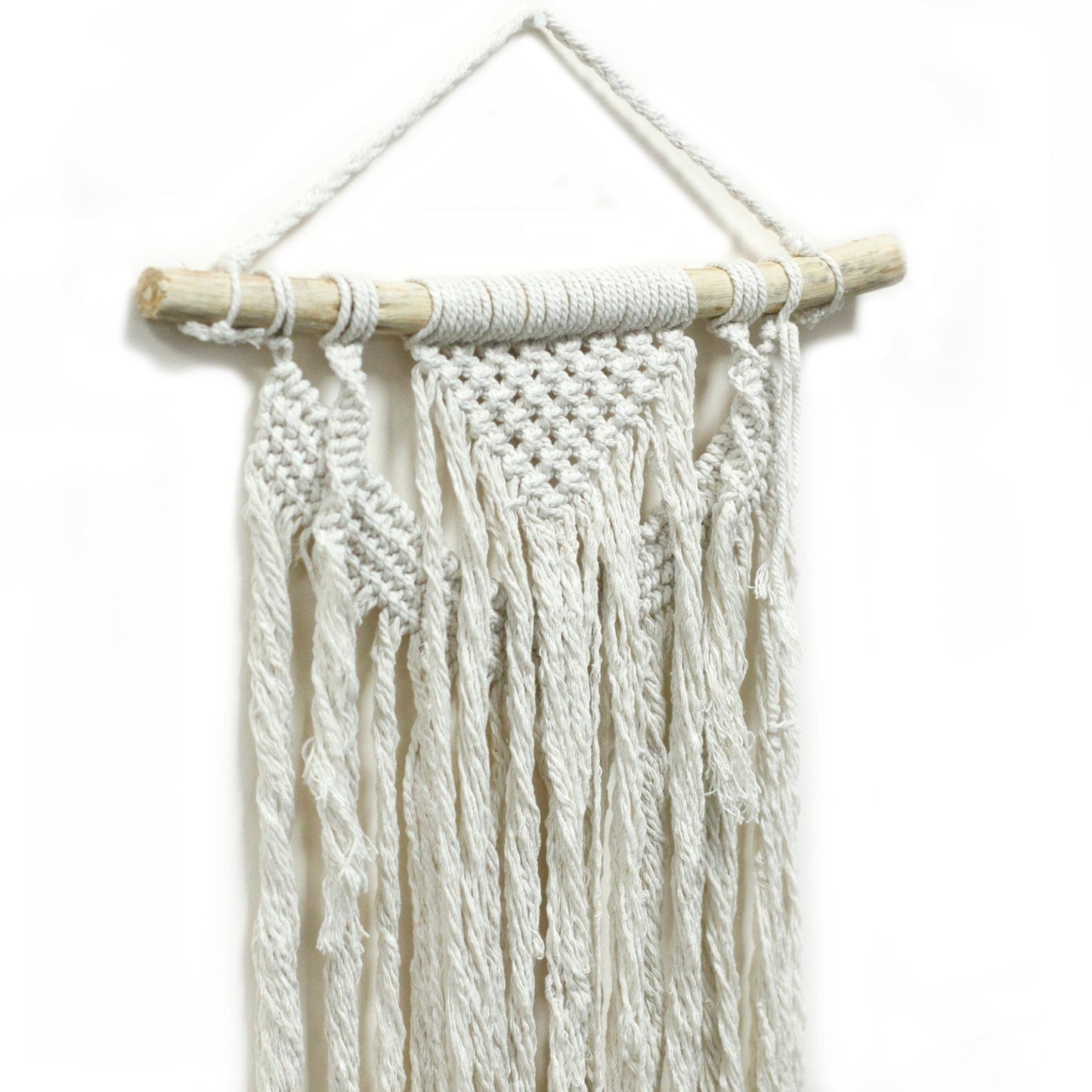 Handcrafted Cotton Macramé Wall Hanging - Force of Nature, close-up of diagonal knotwork, twisted cords and long fringe on a branch by Quintessential Holistic Health Ltd