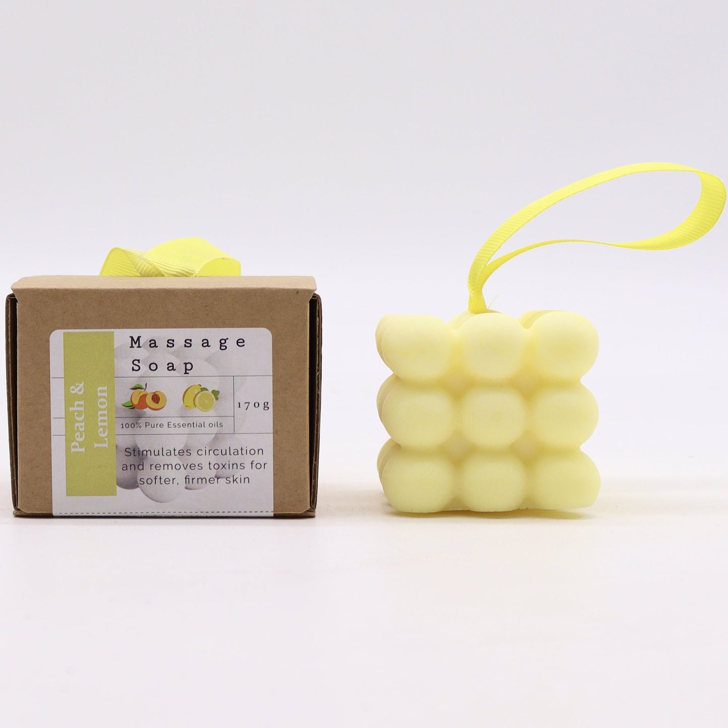 Massage Soap Bar - Peach and Lemon, with a pale yellow bubble design and yellow loop beside a labelled brown box by Quintessential Holistic Health Ltd