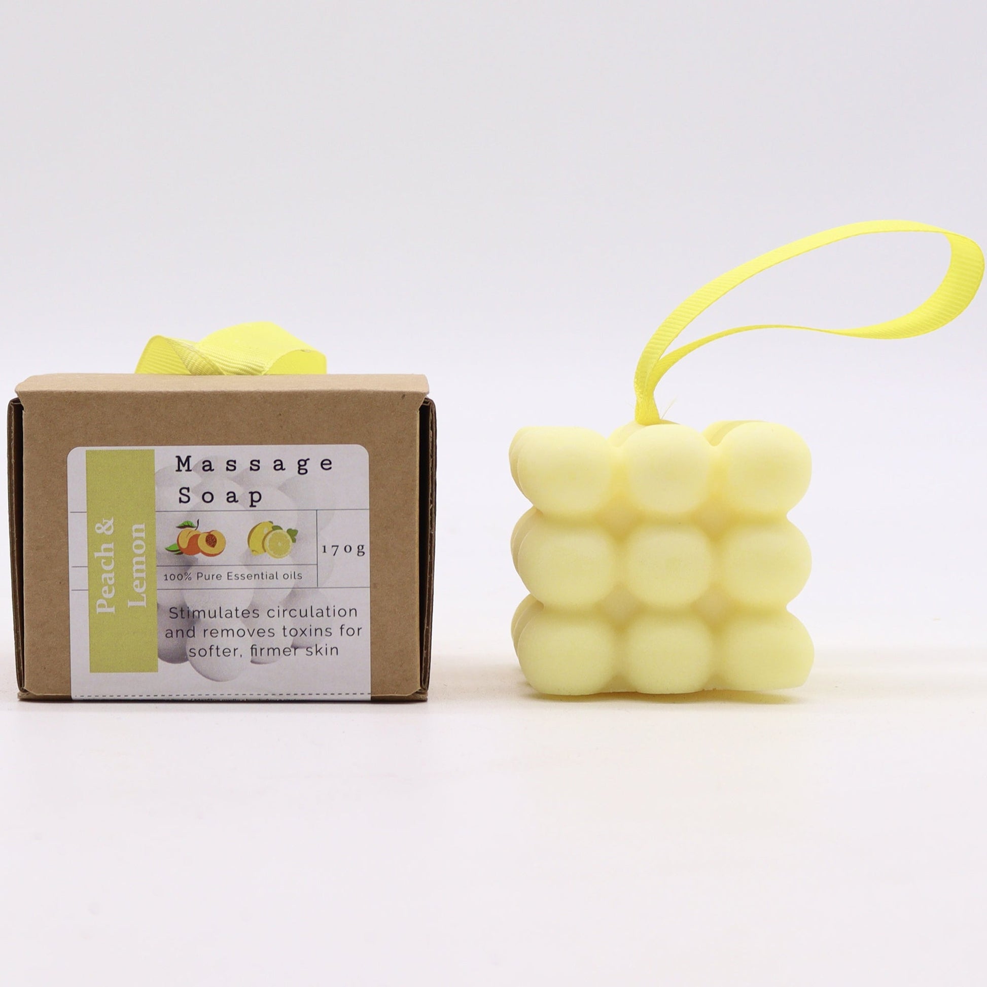 Massage Soap Bar - Peach and Lemon, with a pale yellow bubble design and yellow loop beside a labelled brown box by Quintessential Holistic Health Ltd