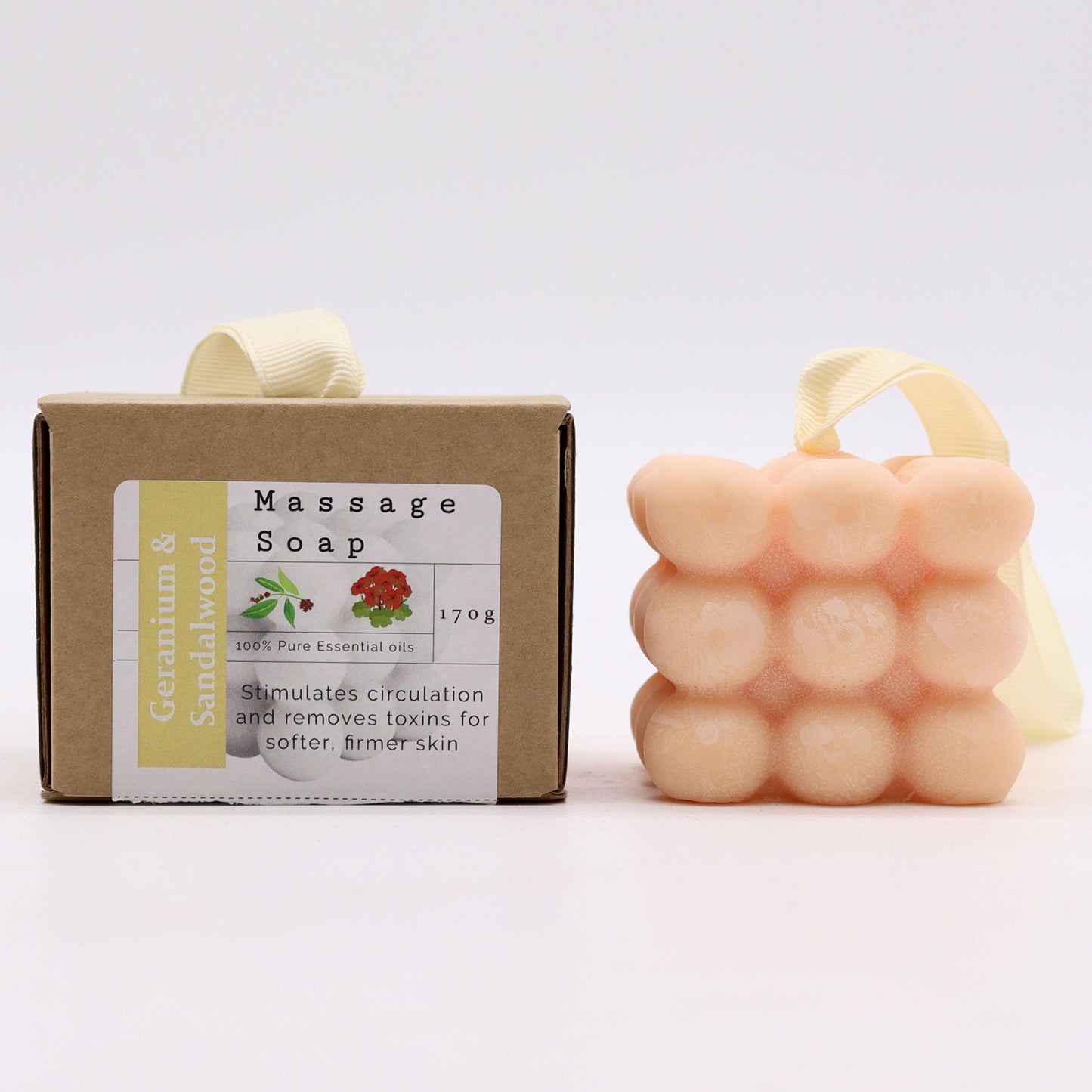 Massage Soap Bar - Geranium and Sandalwood, with a peach bubble design and hanging loop beside a labelled brown box by Quintessential Holistic Health Ltd