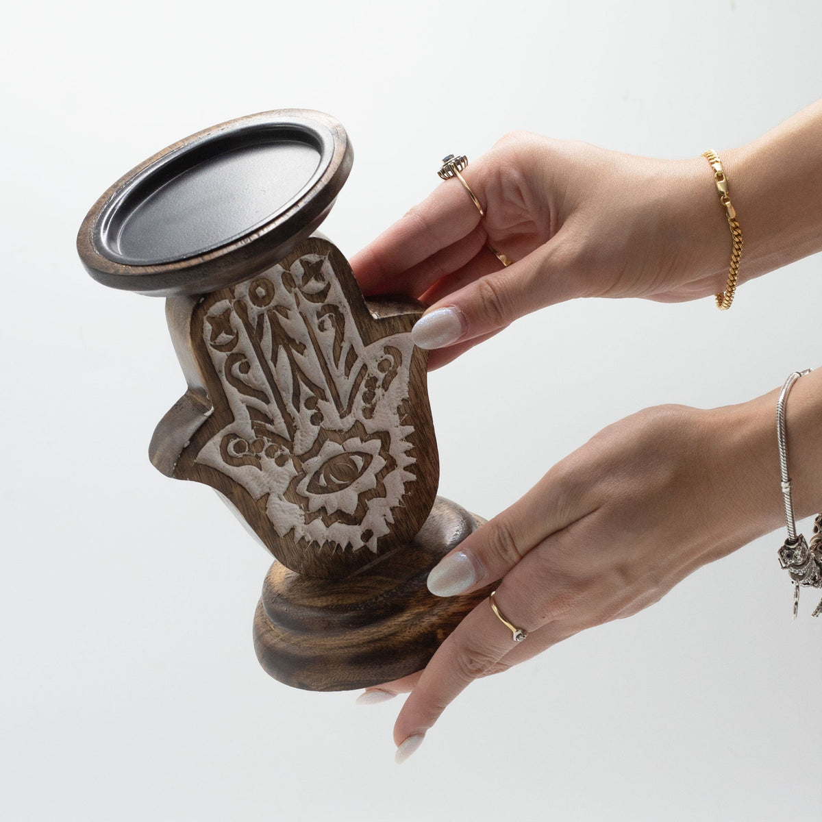 Handmade Mango Wood Hamsa Candle Stand - Small, held in two hands with its decorated face and round top visible, by Quintessential Holistic Health Ltd