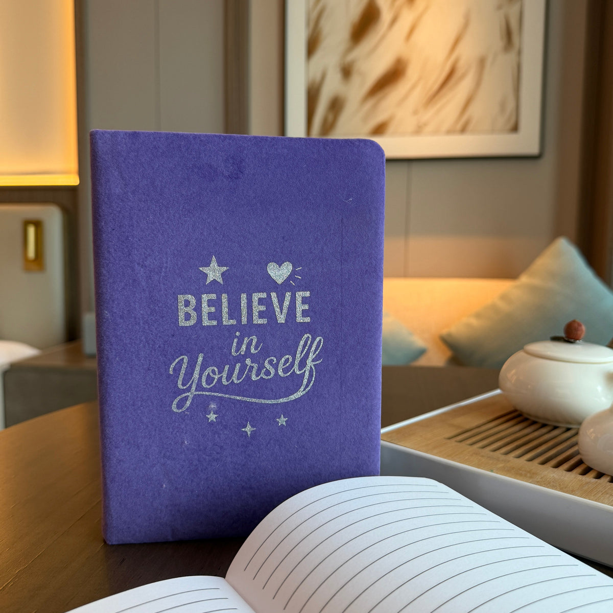 Velvet Journal - A5 - Lavender - Believe in Yourself, upright purple journal beside an open book on a table by Quintessential Holistic Health Ltd