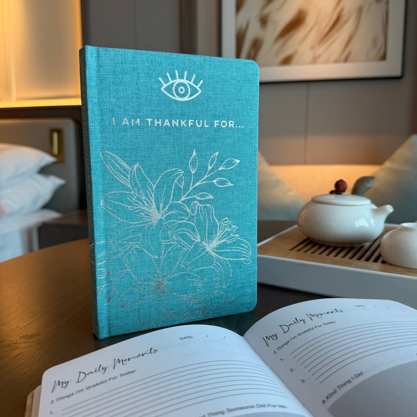 A5 Blue 'I Am Thankful For' Journal with Silver Lining, upright turquoise floral cover beside an open journal by Quintessential Holistic Health Ltd