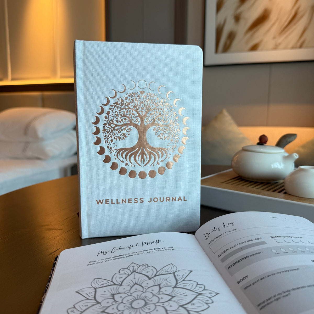 Wellness Journal - A5 - White and Rose Gold - Tree of Life, standing with its tree cover visible beside open illustrated journal pages by Quintessential Holistic Health Ltd
