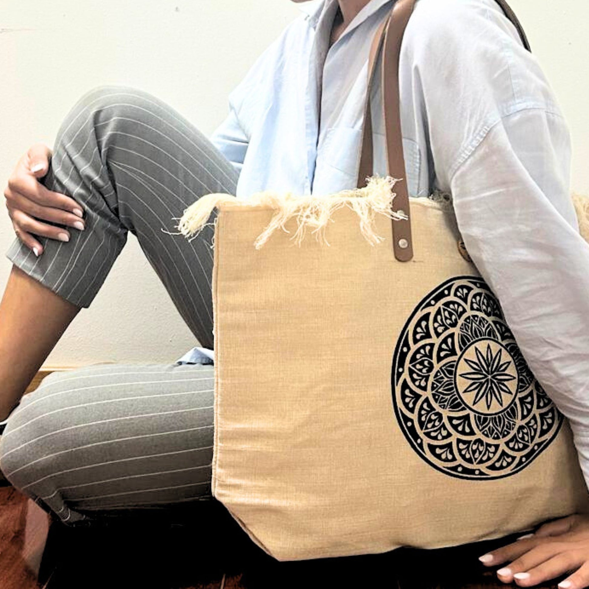 Natural Cotton Tote Bag with Leather Handles - Mandela resting beside a seated model with a bold black circular motif by Quintessential Holistic Health Ltd