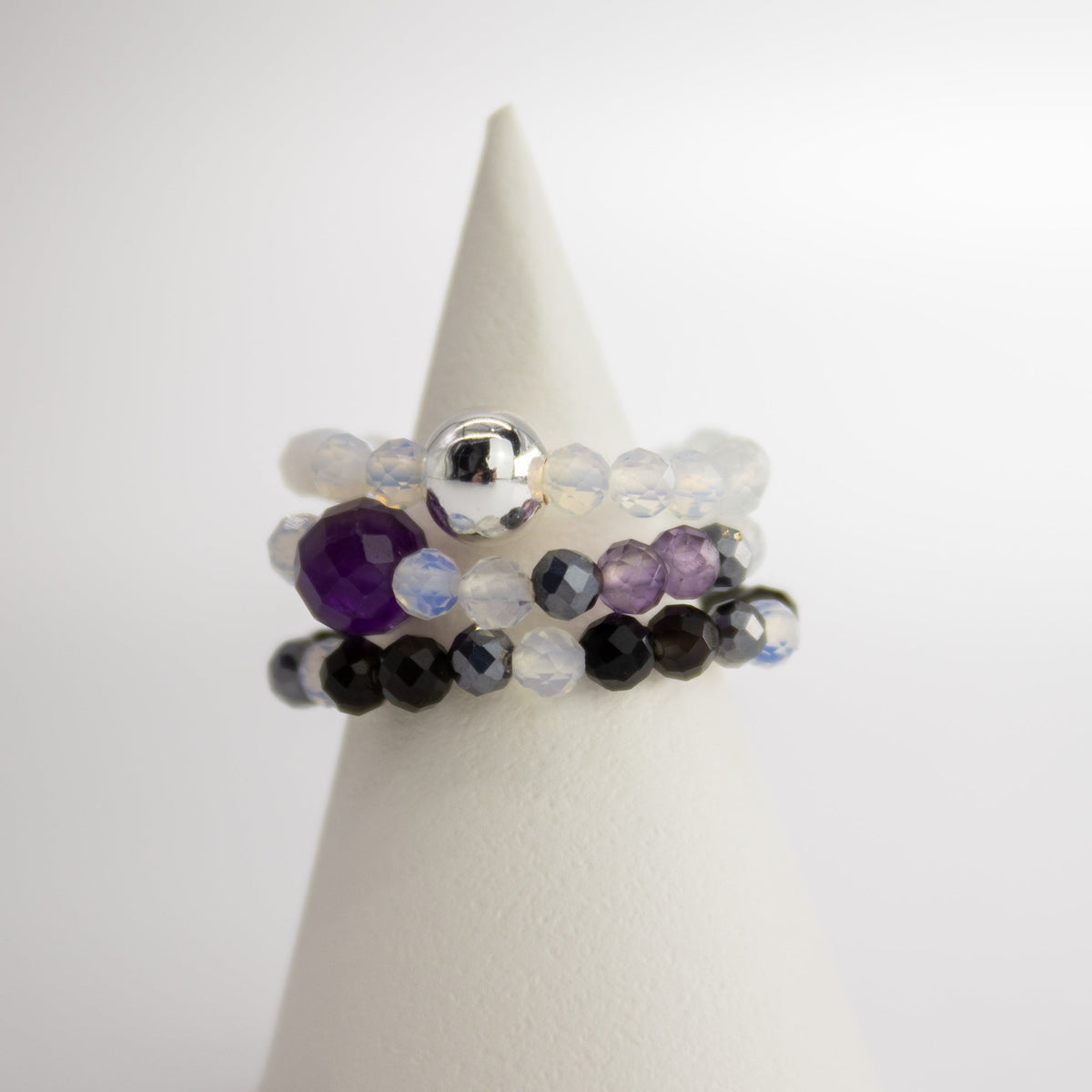 Mystical Nymph Spirit Gemstone 3-Ring Set – Full Moon, purple, black, translucent and silver-toned beaded rings stacked on a white cone, by Quintessential Holistic Health Ltd